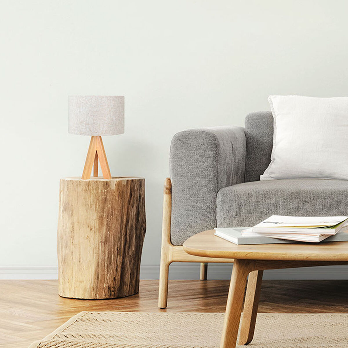 Eine Lampe auf einem Holzständer, Sofa, Couchtisch und Teppich auf einem Holzboden.