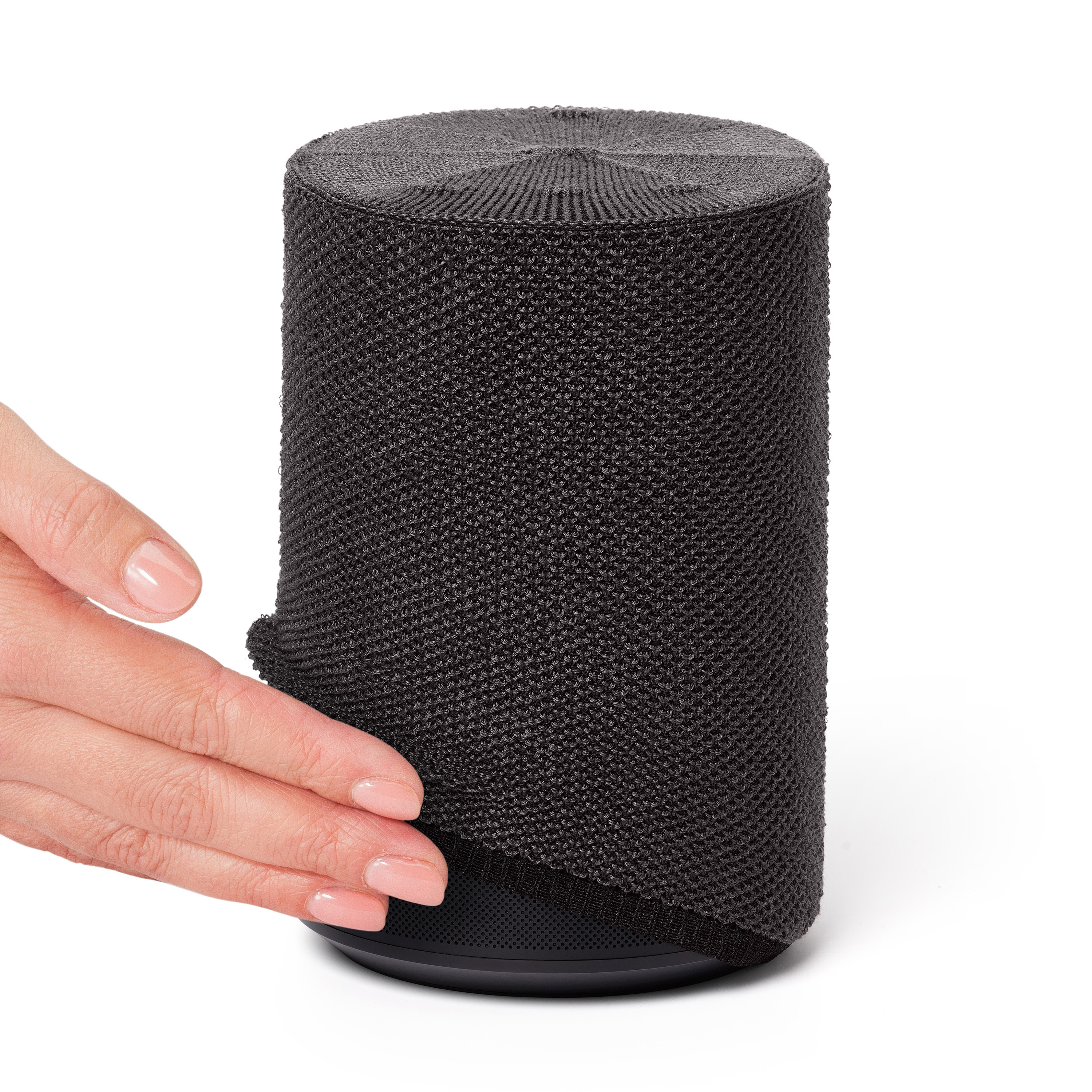 Een hand raakt een zwarte cilindrische luidspreker met een mesh-hoes aan.
