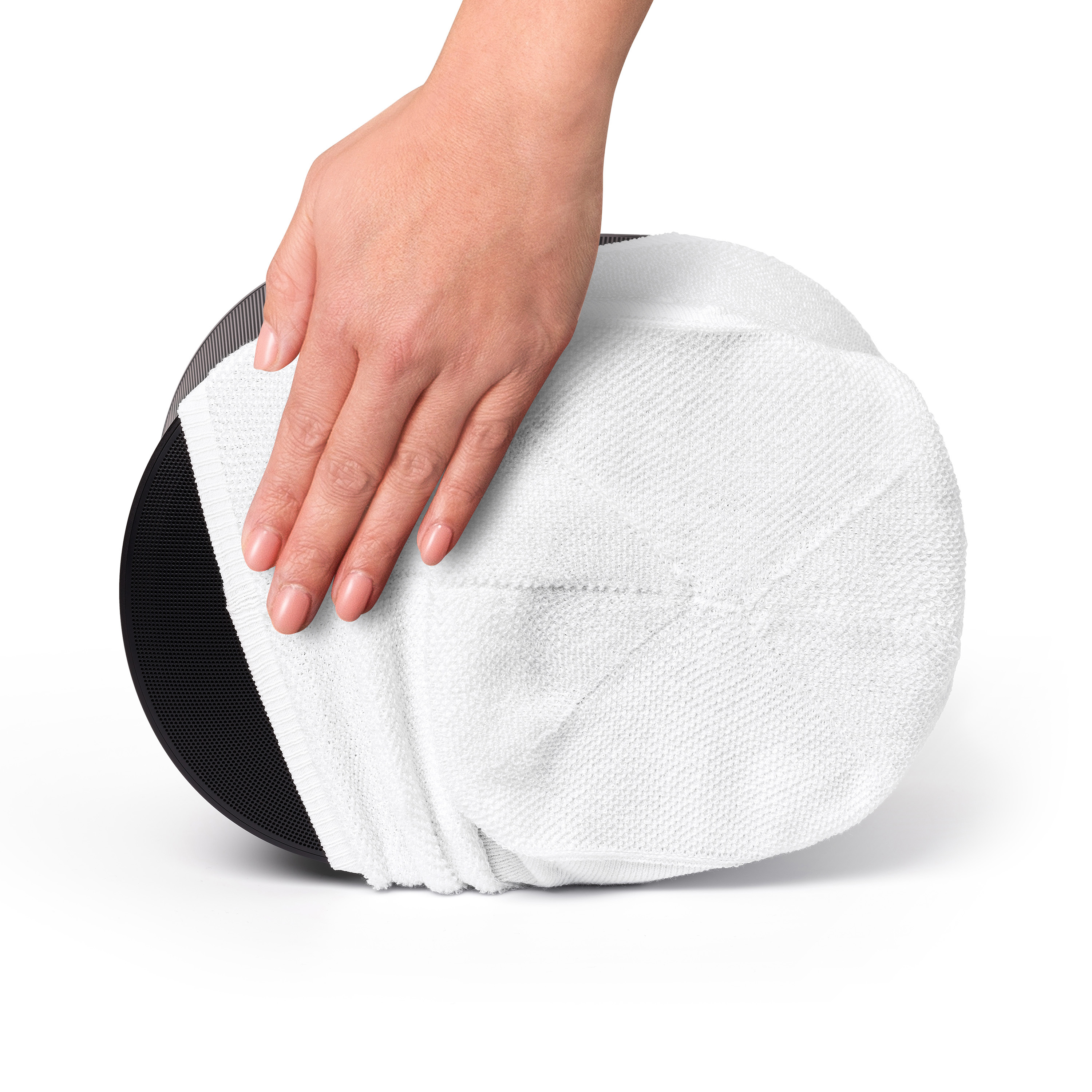 Een hand die een witte, ronde microvezel filterpad aanraakt. De pad ligt op een zwart object.