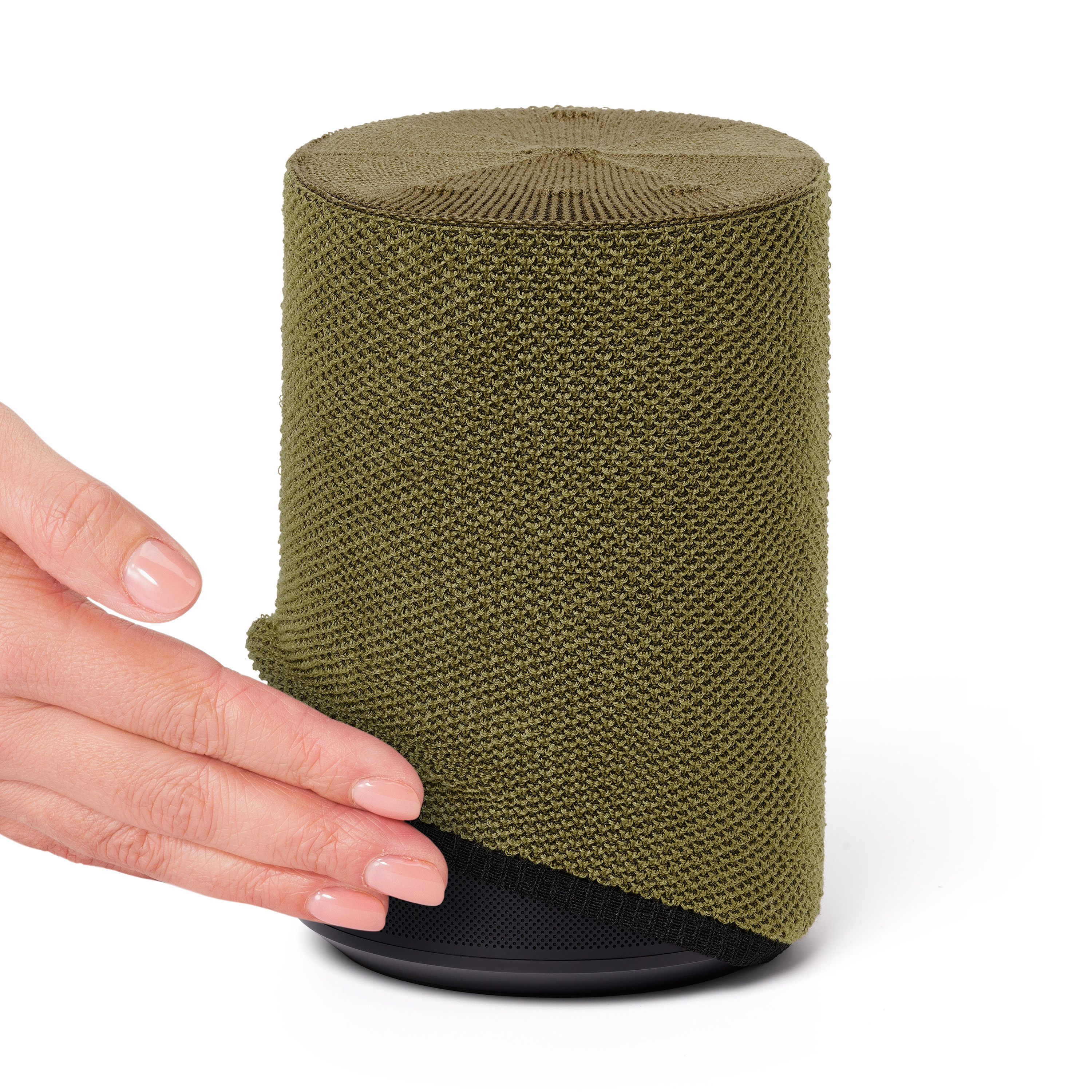 Groene luidspreker bedekt met een gebreide stof. Een hand raakt de stof aan.