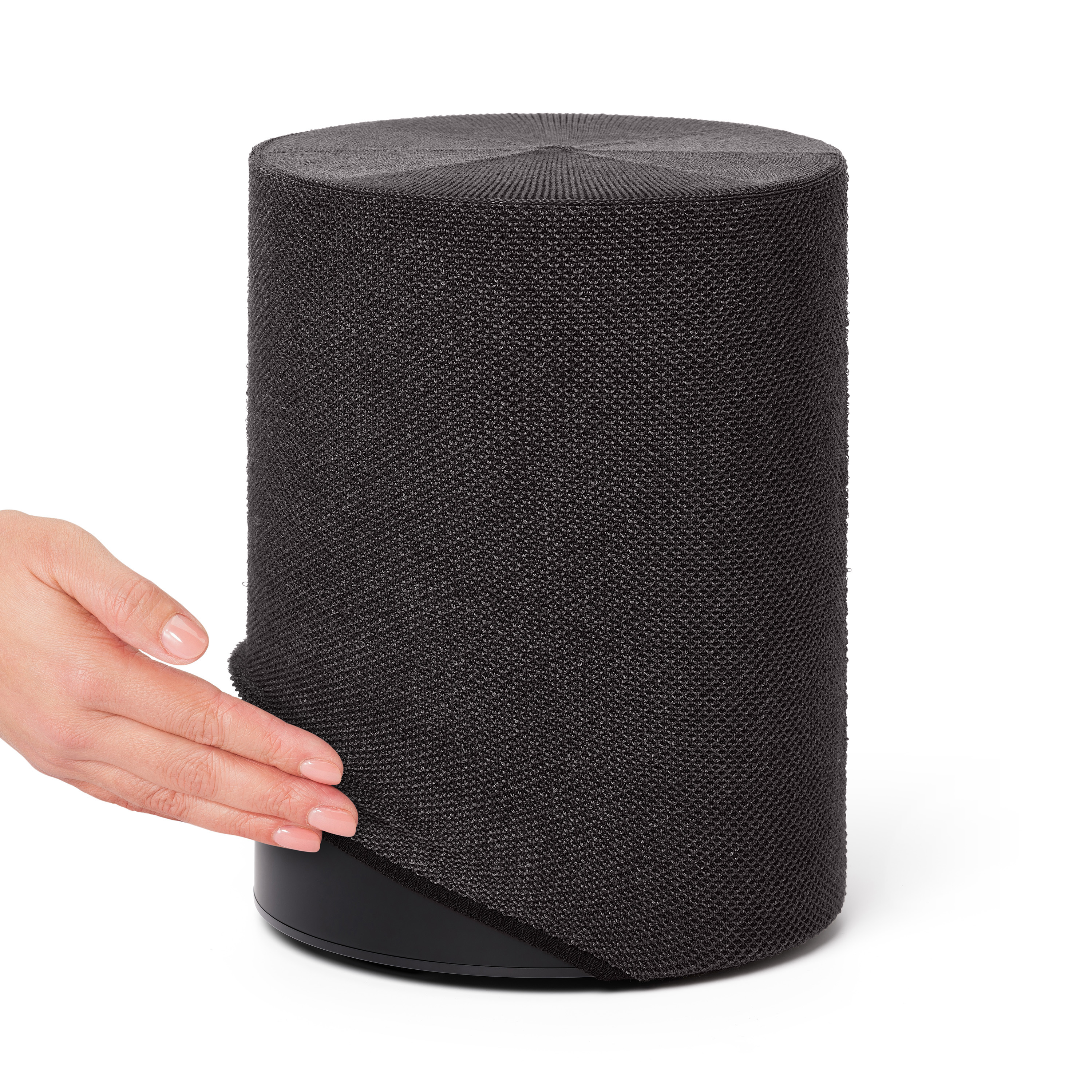 Un haut-parleur cylindrique gris foncé avec une main touchant son tissu.