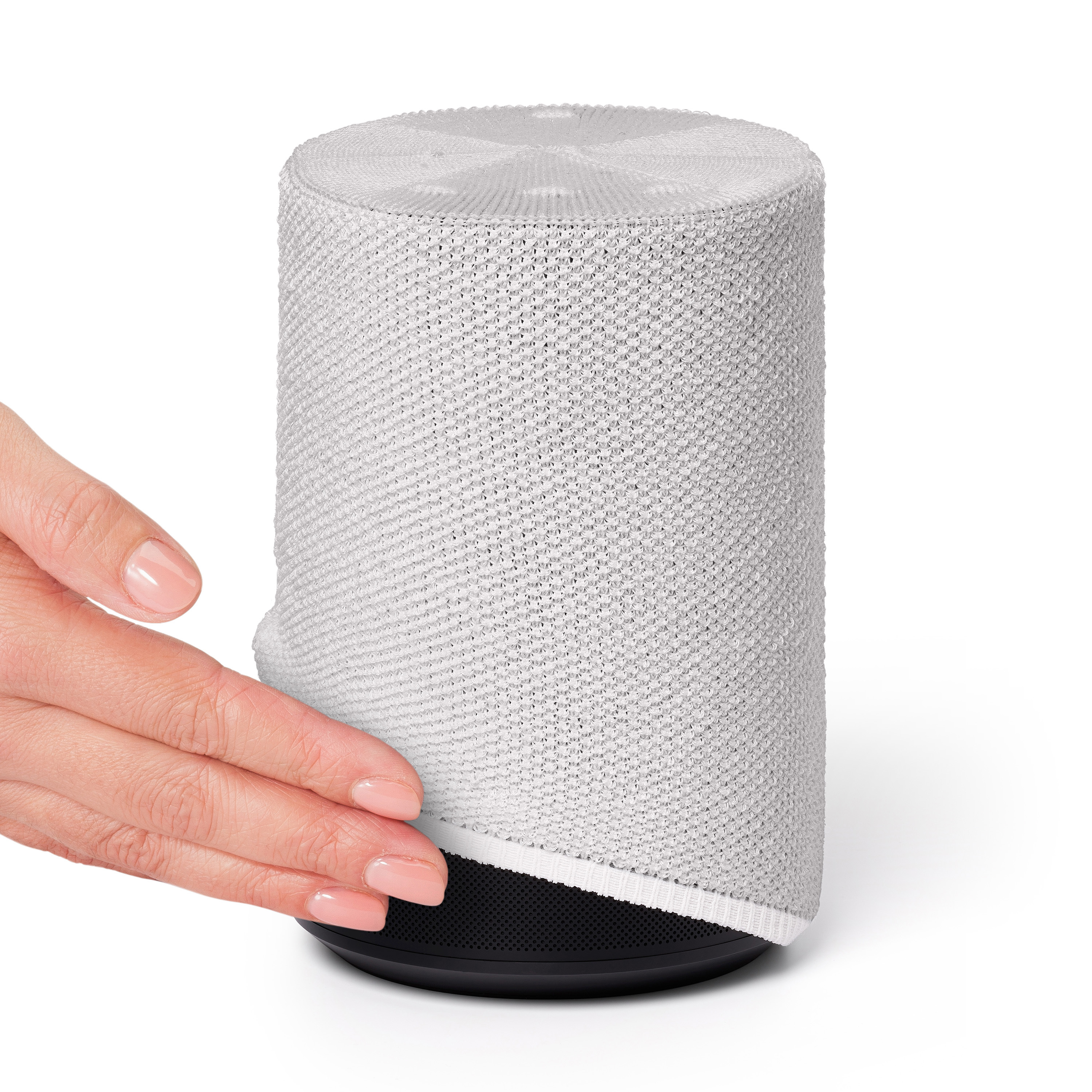 Hand van een vrouw die een witte gebreide luidspreker aanraakt. Zwarte basis, witte gebreide stof omwikkelt de luidspreker.