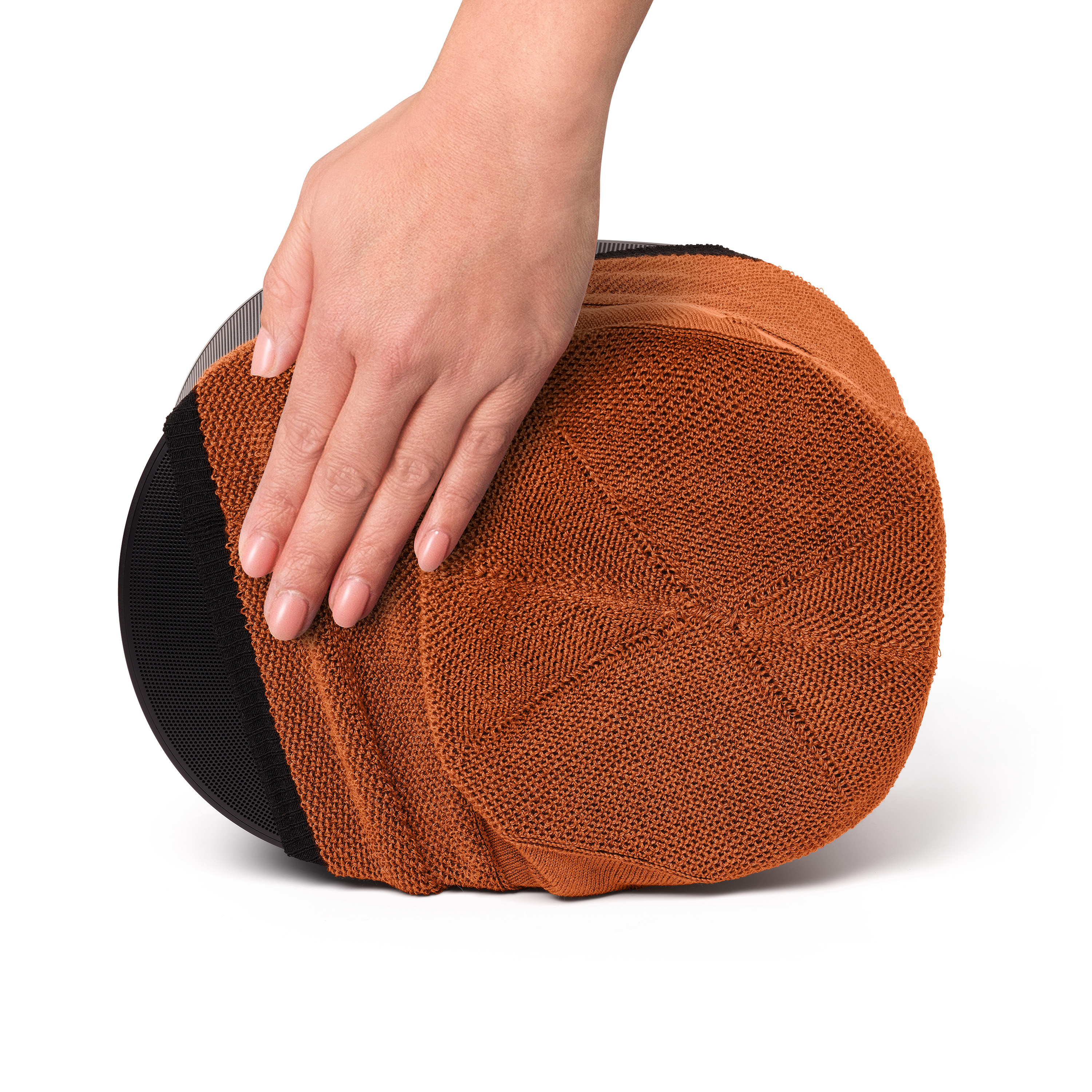 Een hand die een oranje gebreide muts aanraakt. De muts staat op een witte achtergrond. De textuur is zichtbaar.