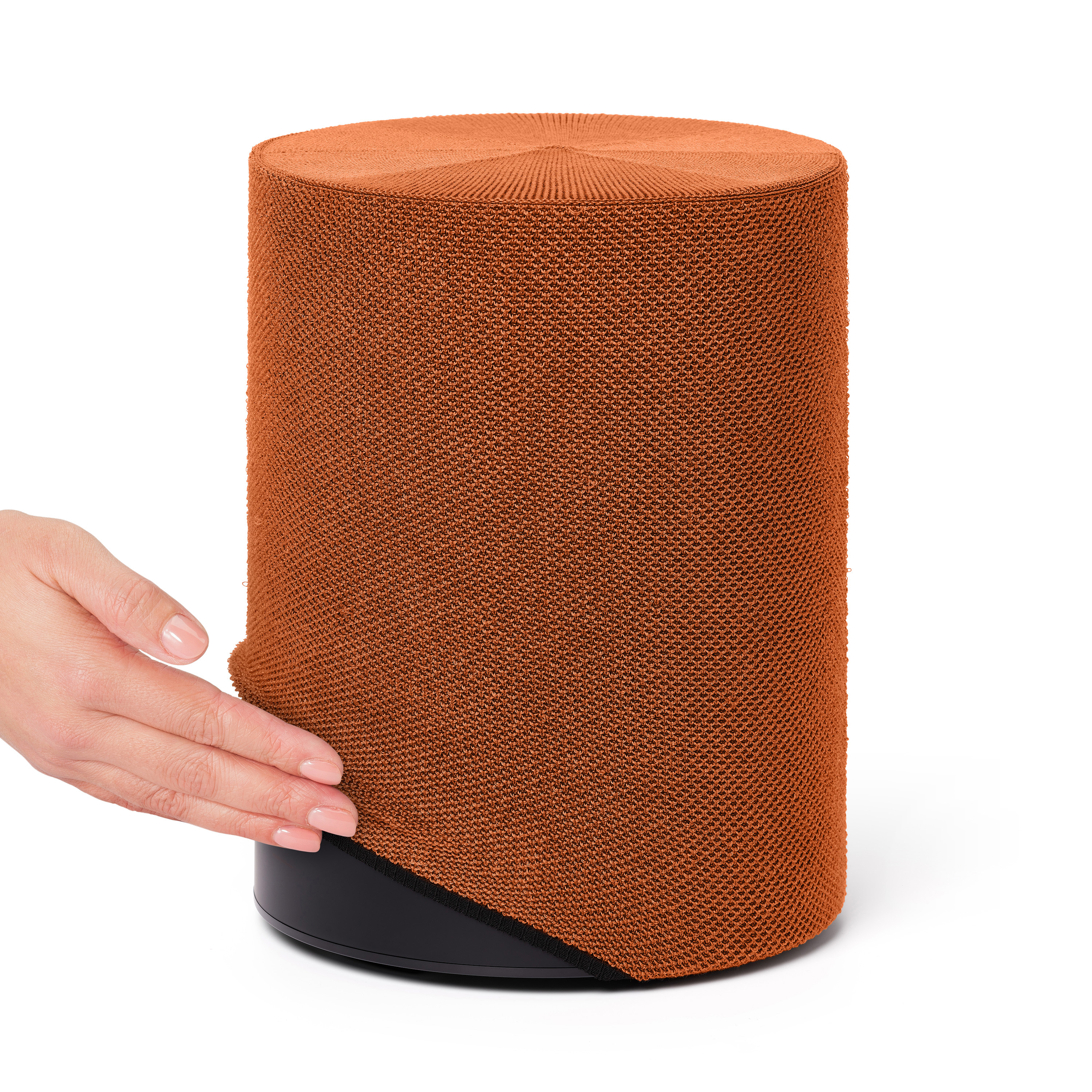 Une main touchant un haut-parleur orange. Le haut-parleur a une base noire et une housse tissée.
