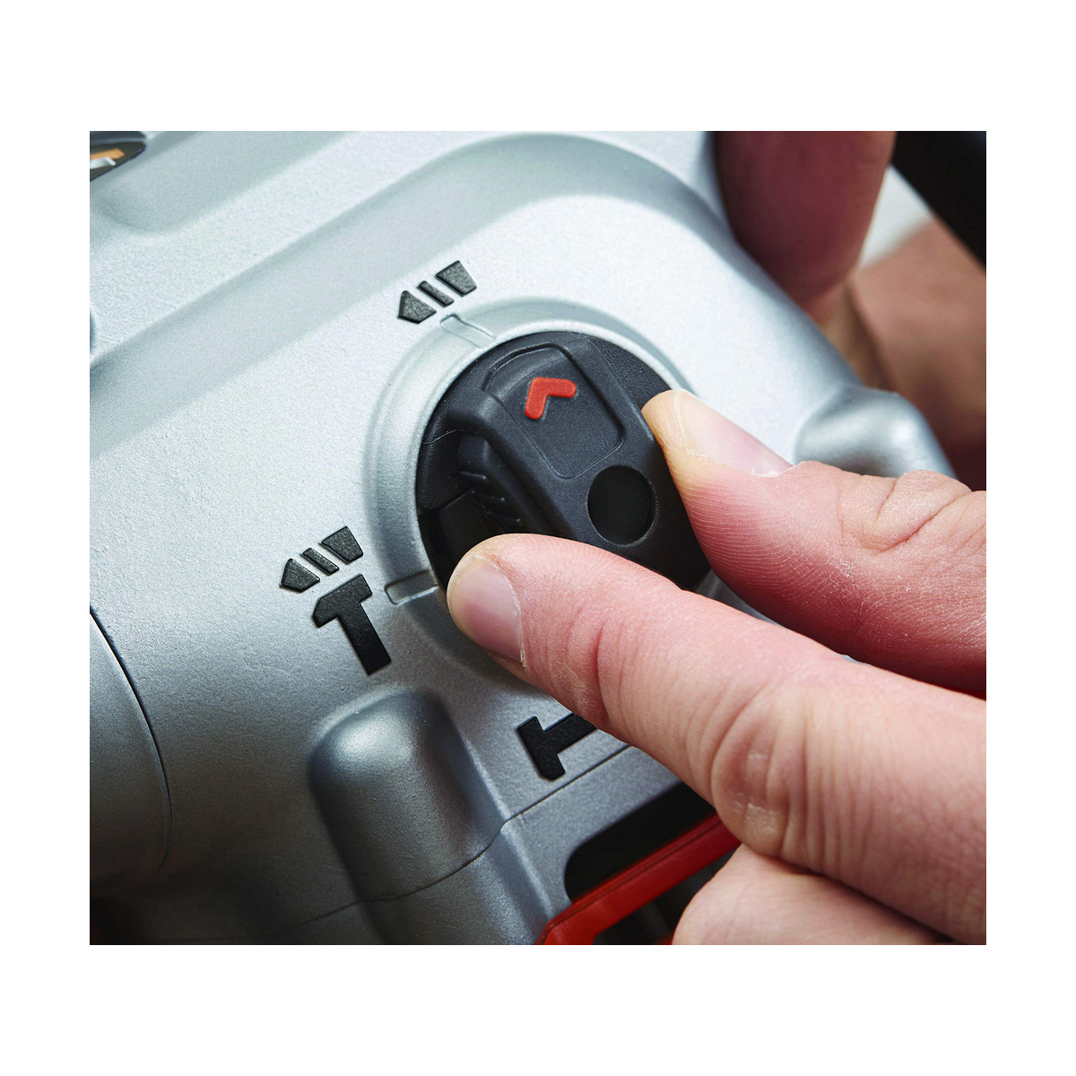 Eine Hand stellt einen schwarzen Drehregler an einem silbernen Elektrowerkzeug ein.