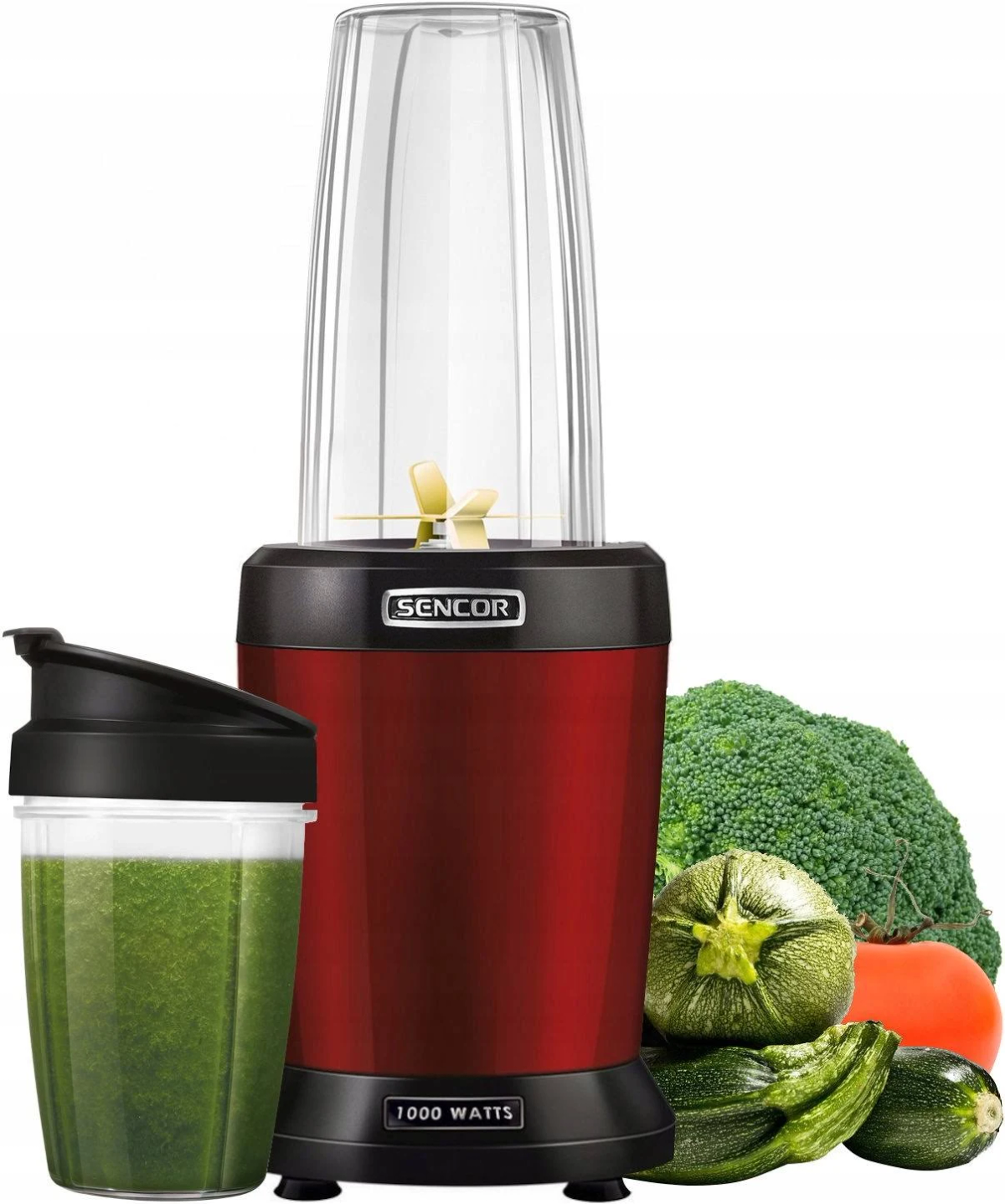 Una licuadora roja con un recipiente transparente, un vaso con batido verde y verduras.