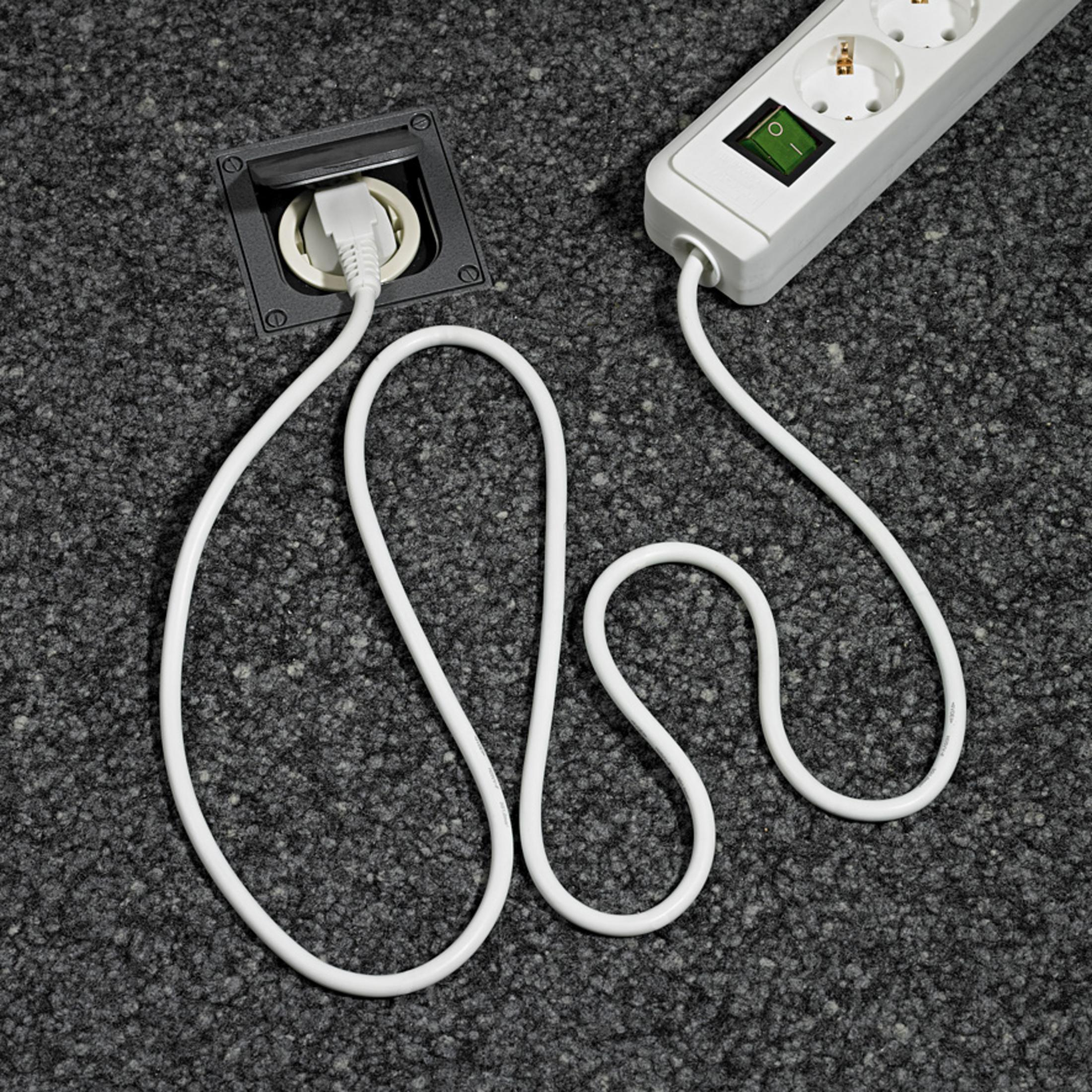 Un cable eléctrico blanco y una toma de corriente. El cable está conectado a ambos.