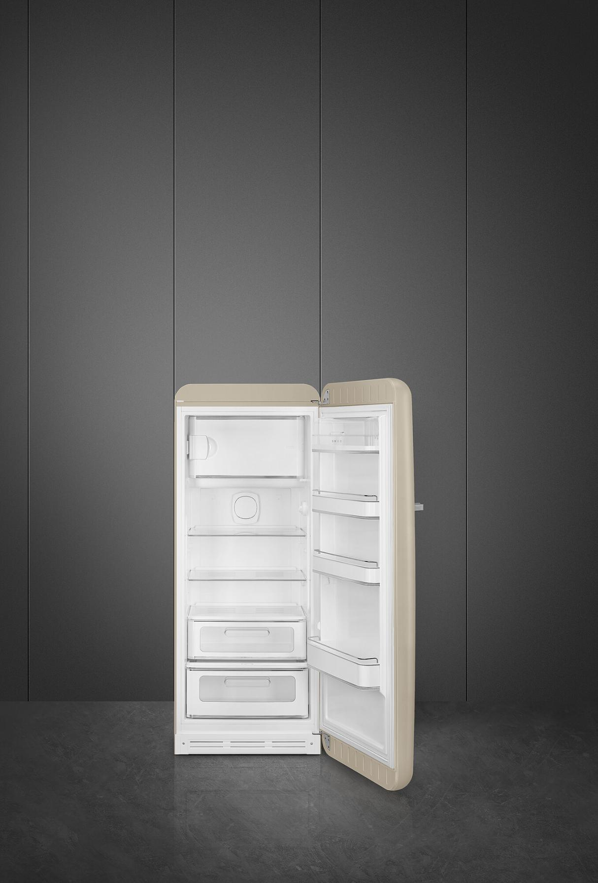 Nevera retro beige, abierta, sobre suelo gris contra pared gris. Vacía por dentro.