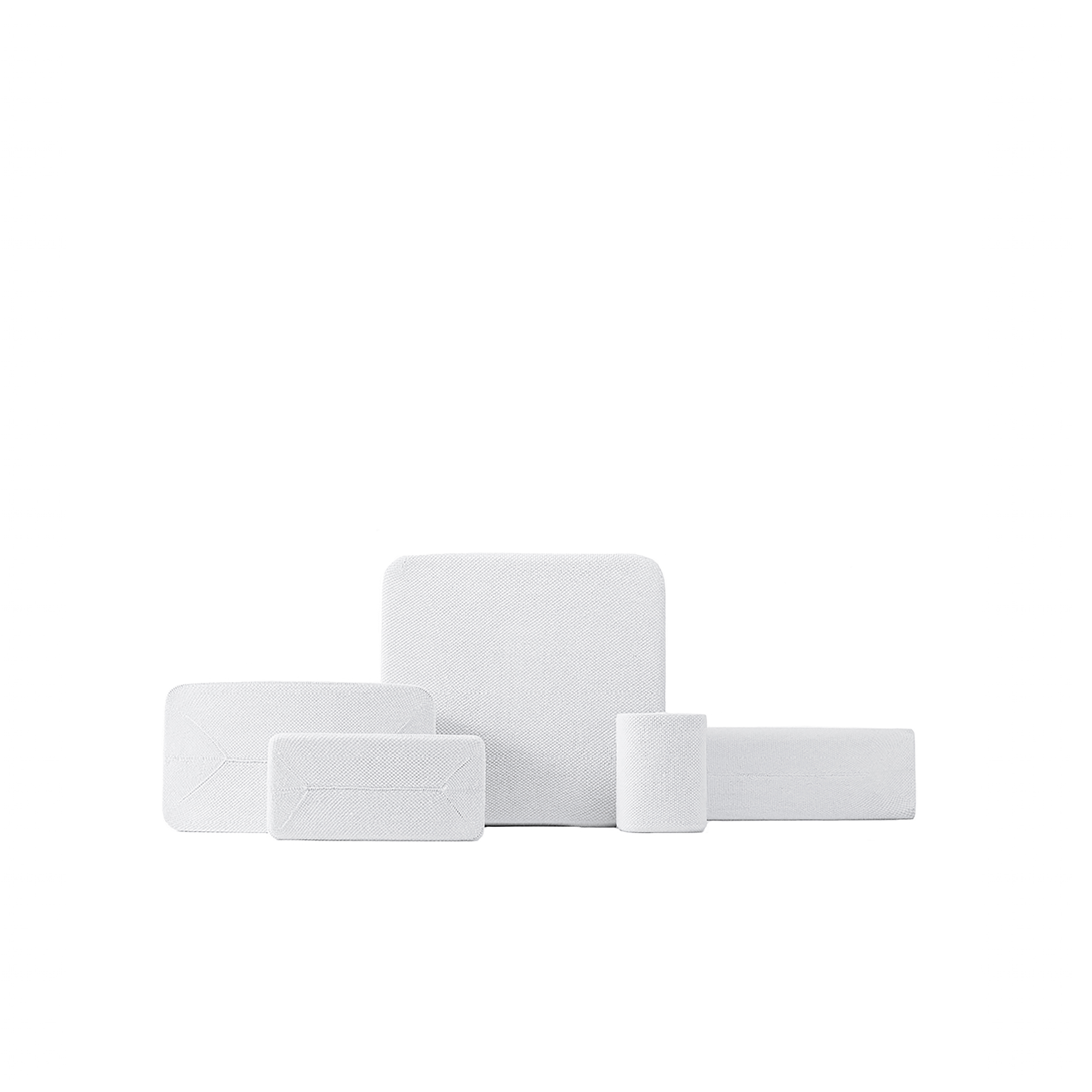 Une collection de pansements en mousse blanche de différentes formes et tailles, disposés sur fond blanc.