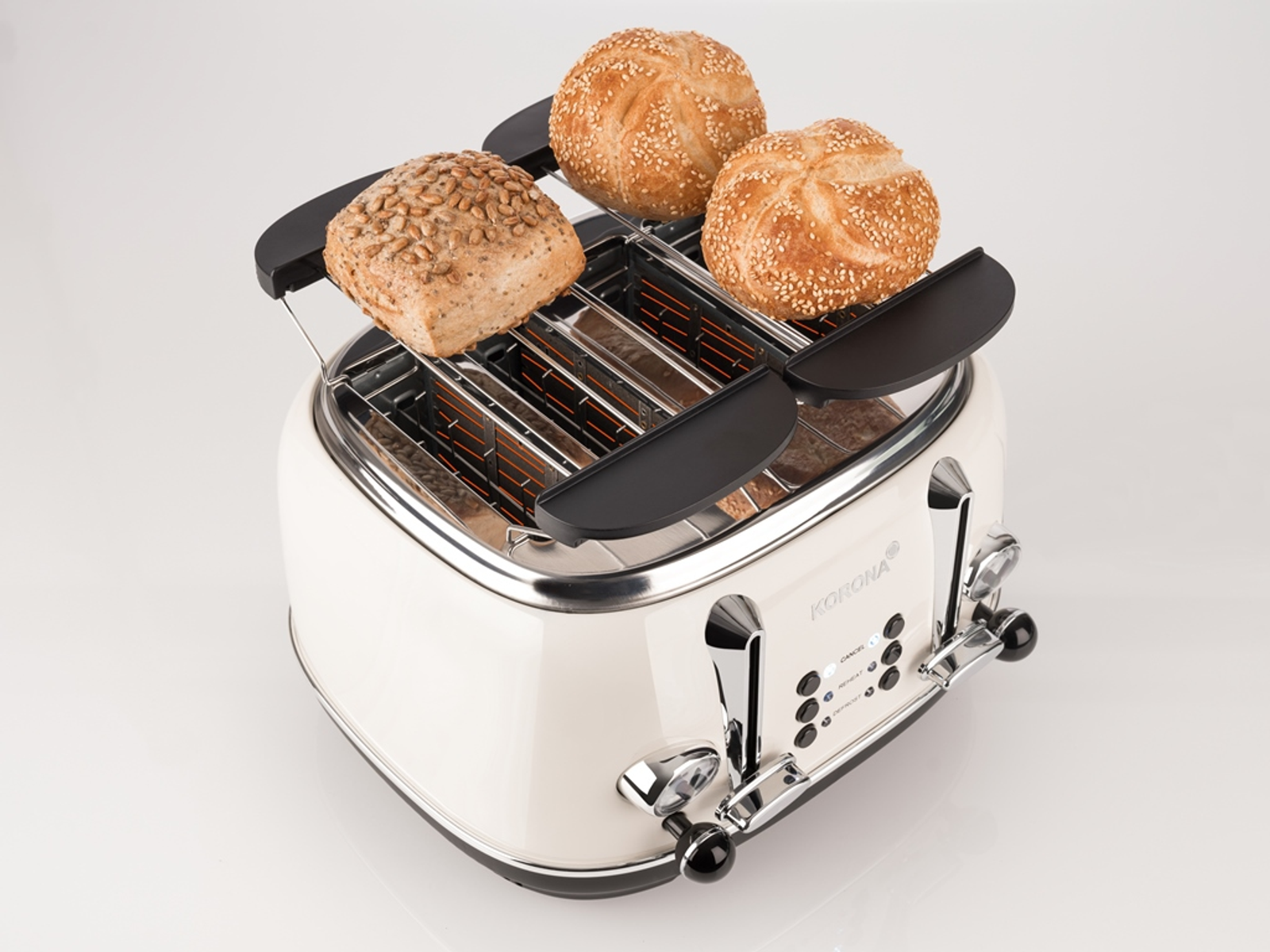 Toster z trzema otworami na chleb i dwoma bułkami na górze, na białej powierzchni.