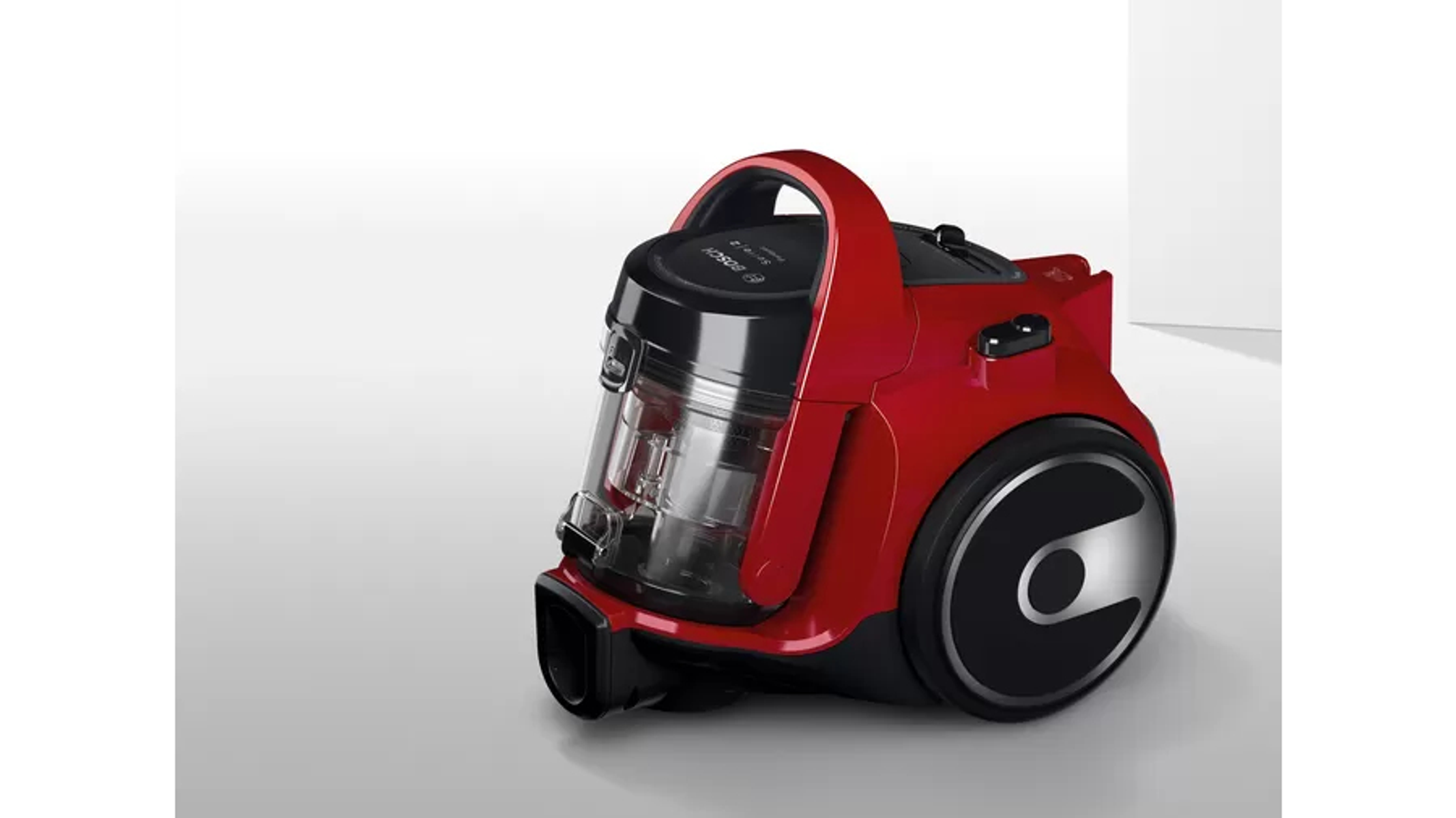 Czerwony odkurzacz na jasnym tle. Widok z boku.