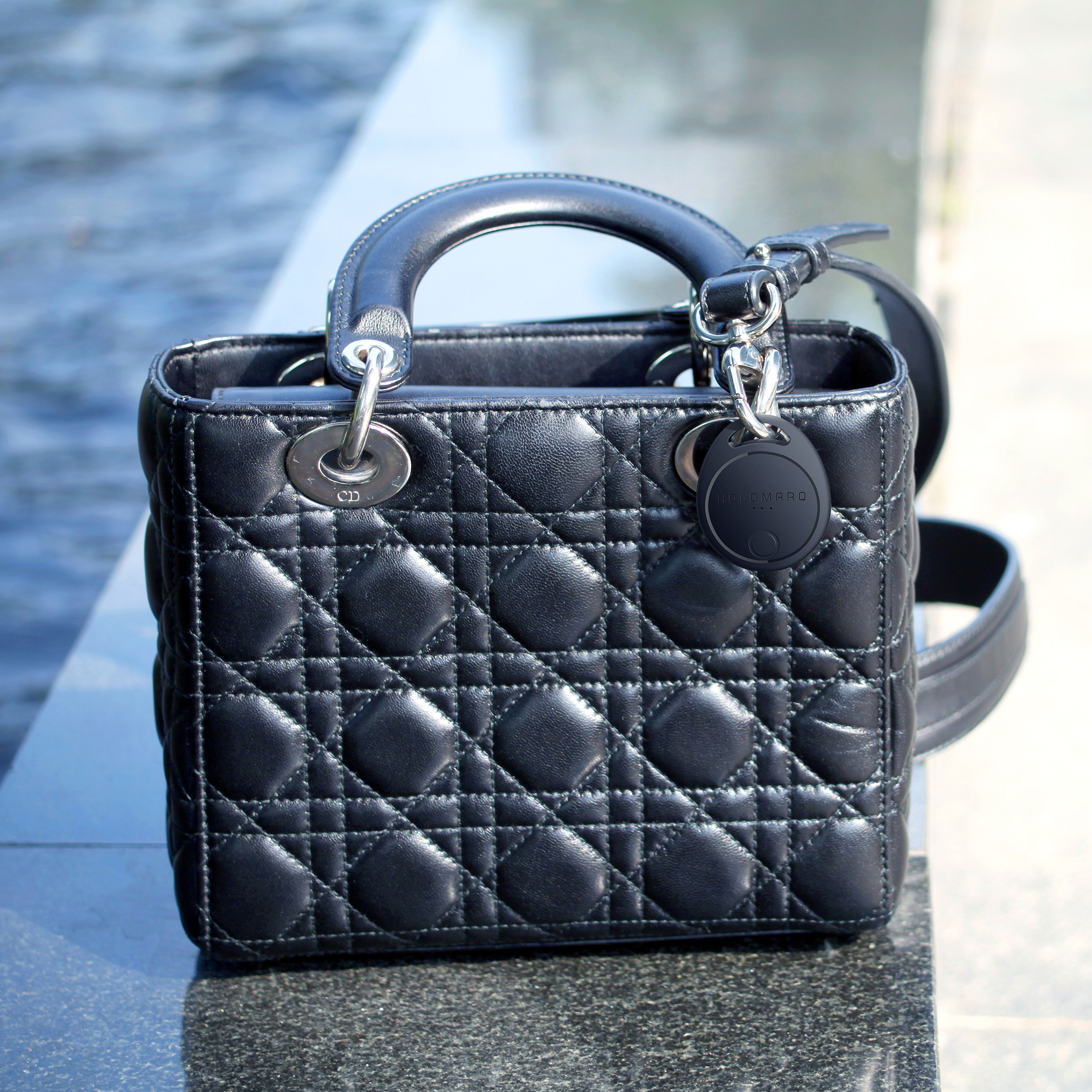 Eine schwarze, gesteppte Lederhandtasche mit silberfarbenen Beschlägen und einem Griff.