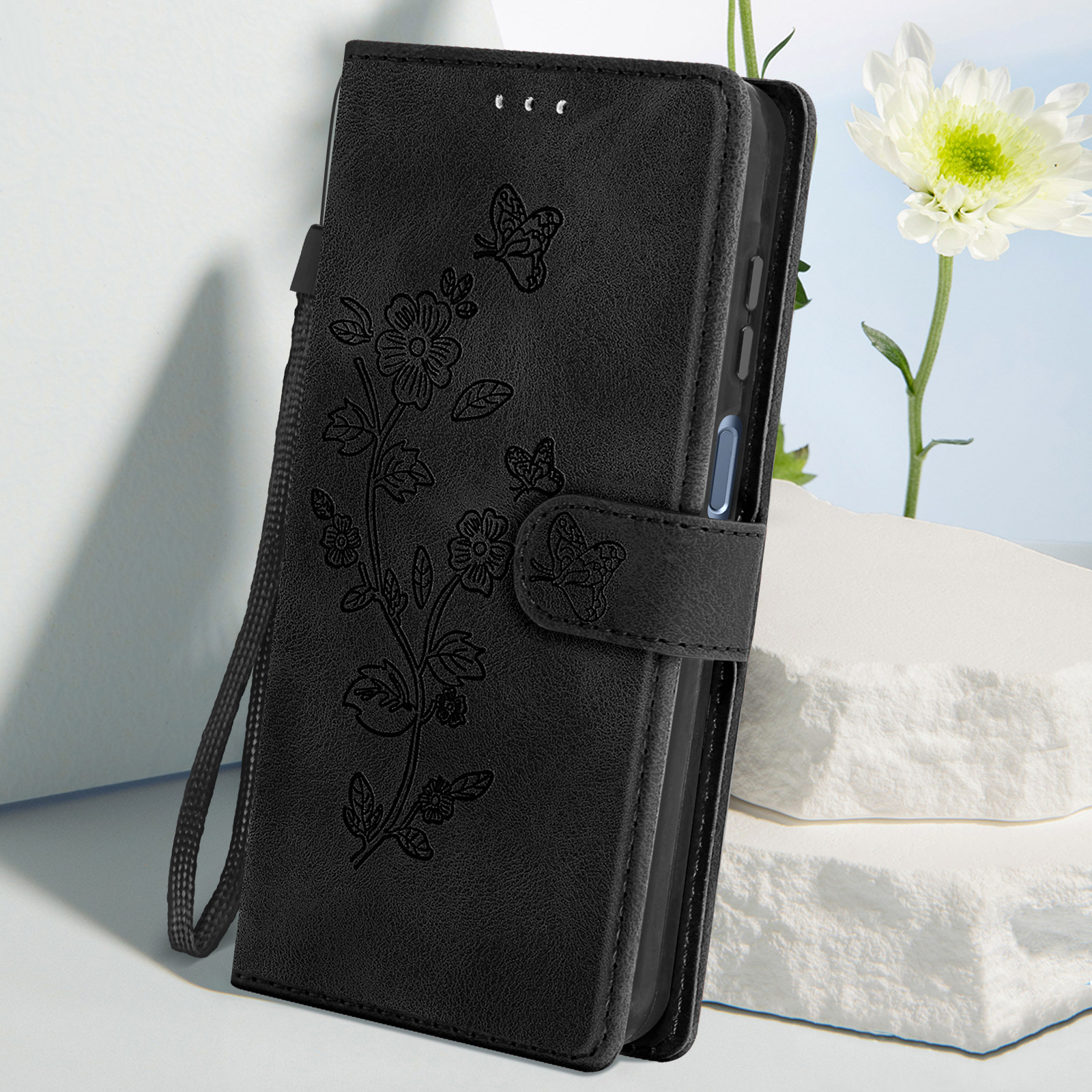 Schwarze Handyhülle mit floralem Design und Schmetterlingen. Offen, mit Telefon innen.