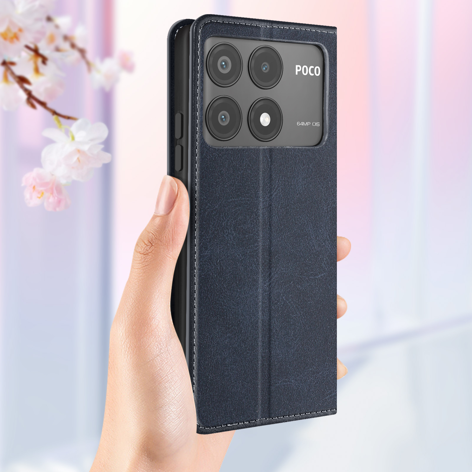 Mano che tiene una custodia per telefono blu scuro. La custodia ha un ritaglio per la fotocamera. Fiori rosa sullo sfondo.