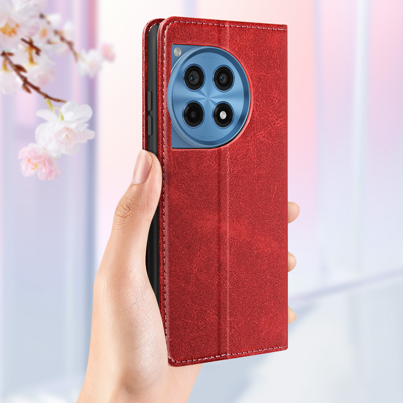 Eine rote Handyhülle mit blauer Kamera, gehalten von einer Hand, mit rosa Blumen im Hintergrund.