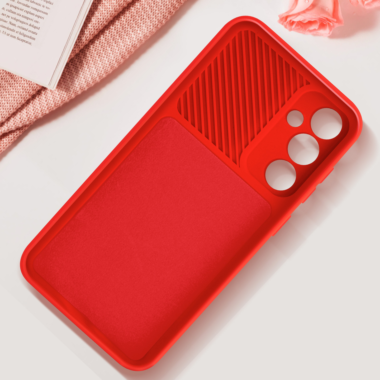 Custodia per telefono rossa, con ritaglio per fotocamera, su una superficie bianca, con un panno rosa.