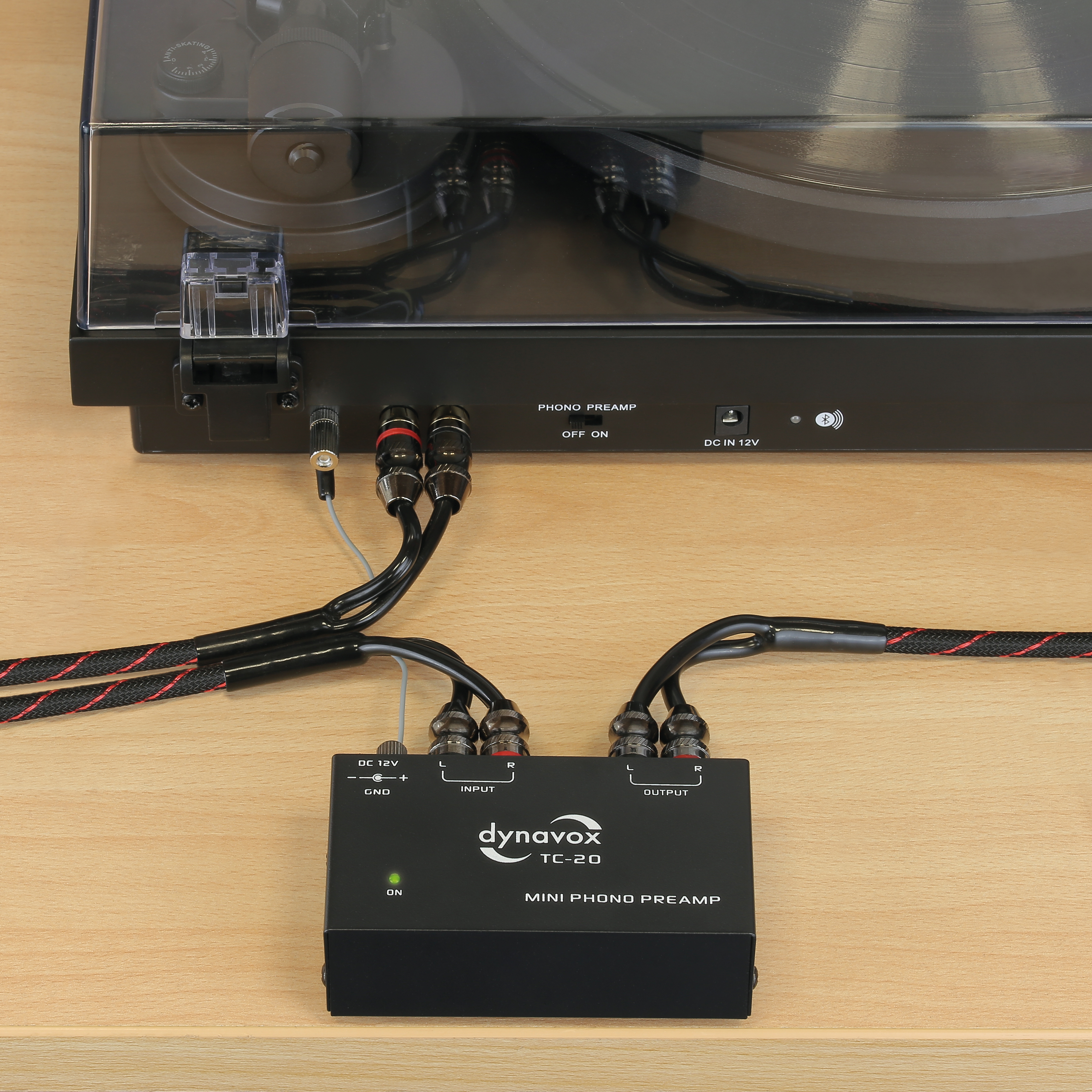 Mini-Phono-Vorverstärker an Plattenspieler angeschlossen. Kabel und Ausgänge sind sichtbar.