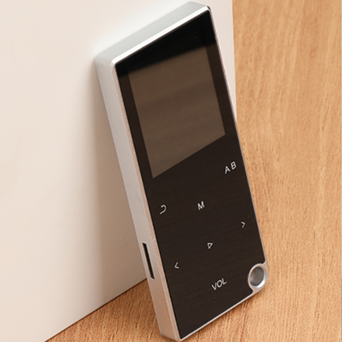 Elegancki, srebrno-czarny cyfrowy odtwarzacz muzyki na drewnianej powierzchni, przechylony w lewo.