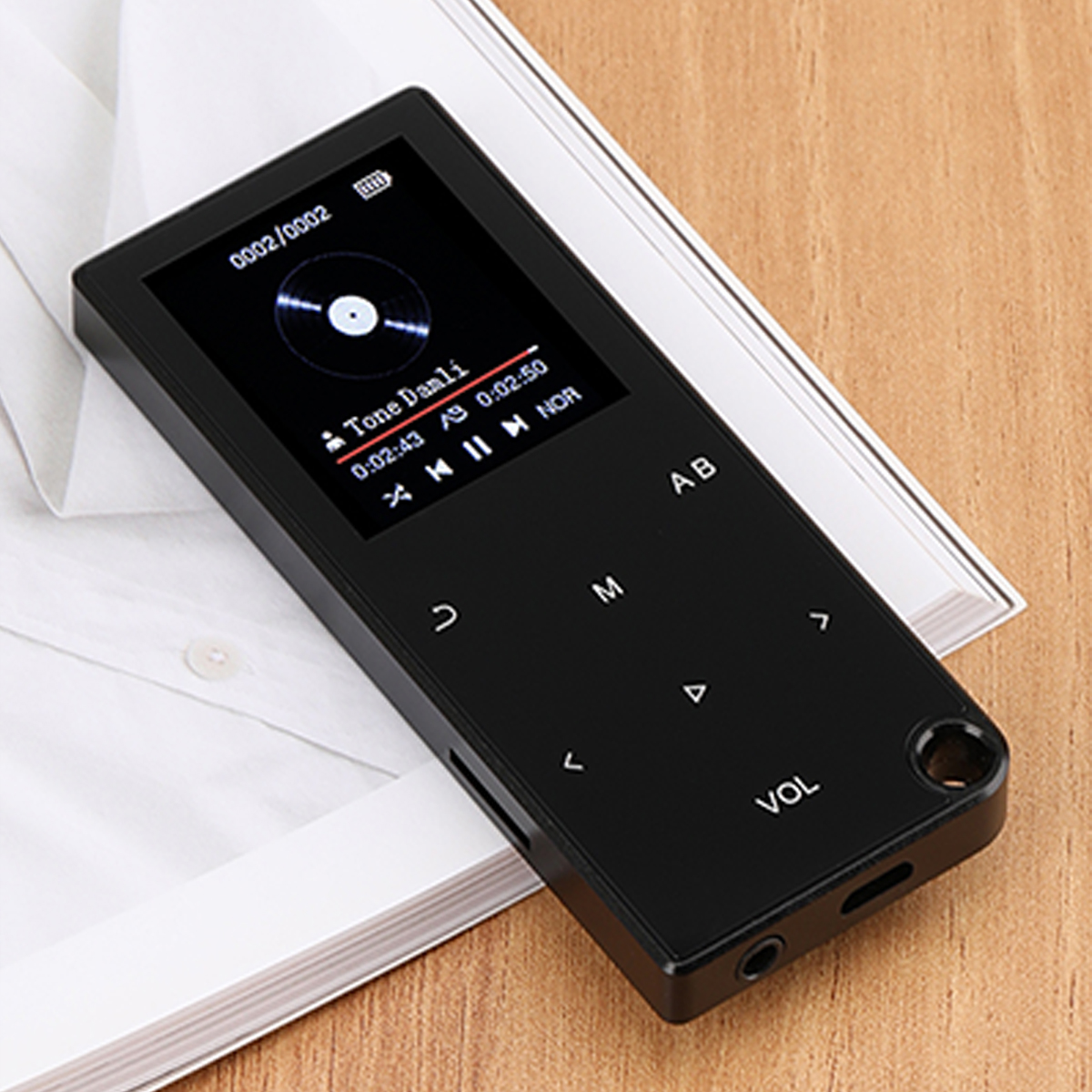 Czarny odtwarzacz MP3 z ekranem wyświetlającym informacje o muzyce. Na drewnianej powierzchni z papierem.