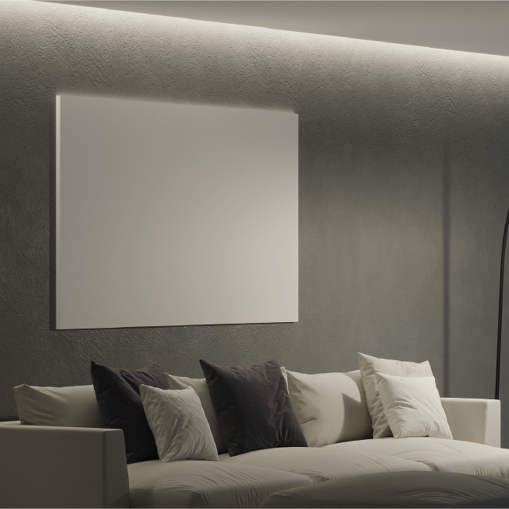 Escena interior con un sofá blanco, almohadas oscuras y un lienzo en blanco enmarcado en una pared gris oscura.