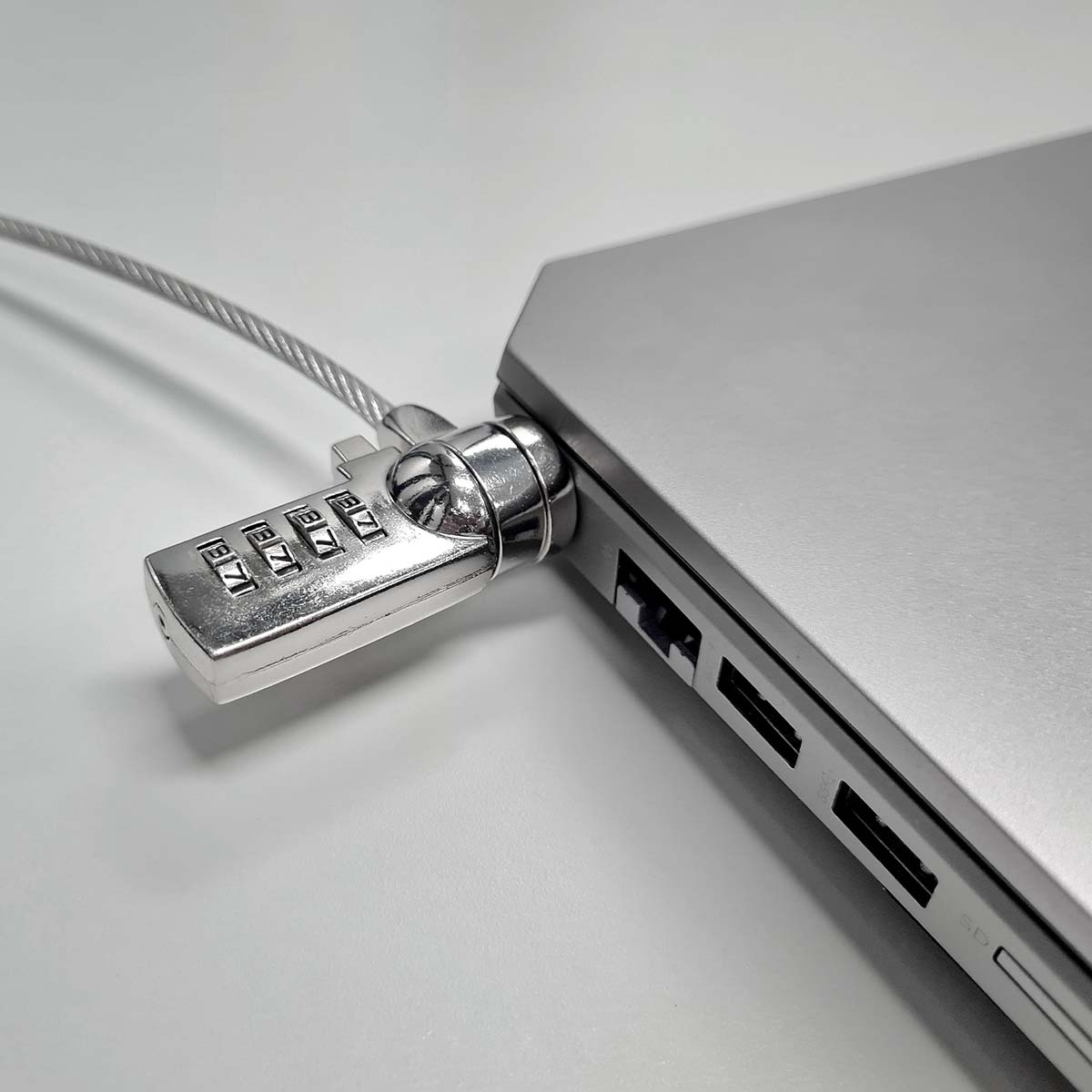 Ein silberner Laptop mit Sicherheitskabel und Zahlenschloss an der Seite.