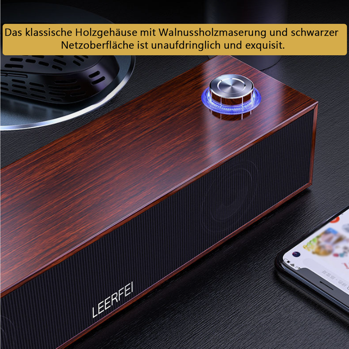 Altavoz de madera con acabado de veta y malla negra. Perilla con luz azul, smartphone visible.