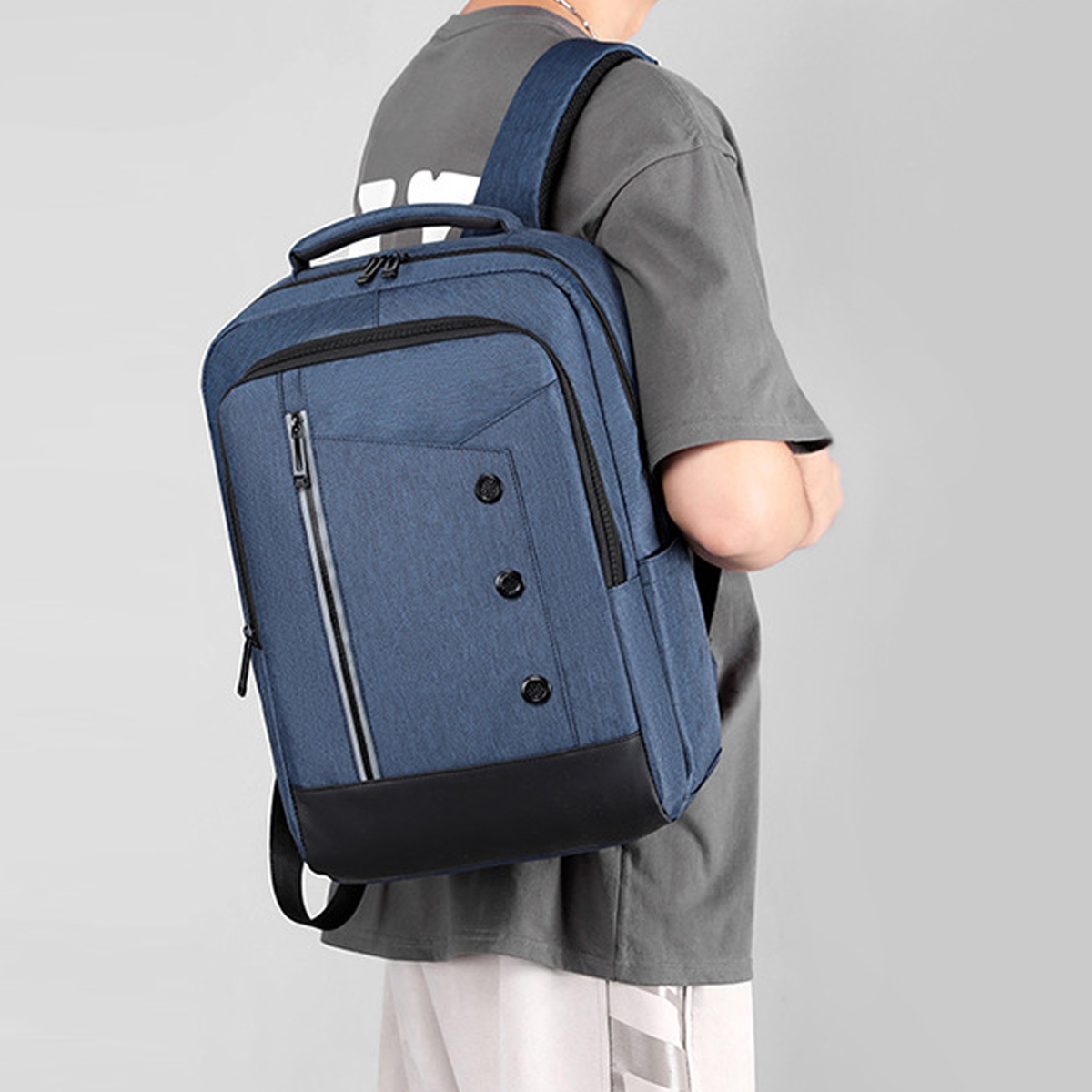 Person mit blauem Rucksack mit schwarzen Akzenten, grauer Hintergrund.