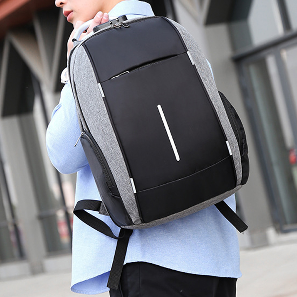Ein Mann trägt einen grau-schwarzen Rucksack mit weißem Streifen.