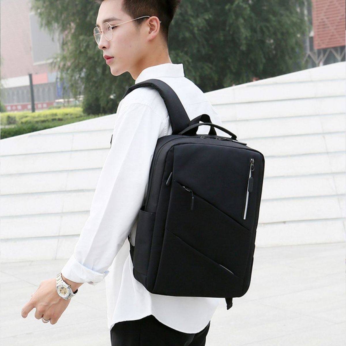 Mann mit Brille und weißem Hemd mit schwarzem Rucksack.