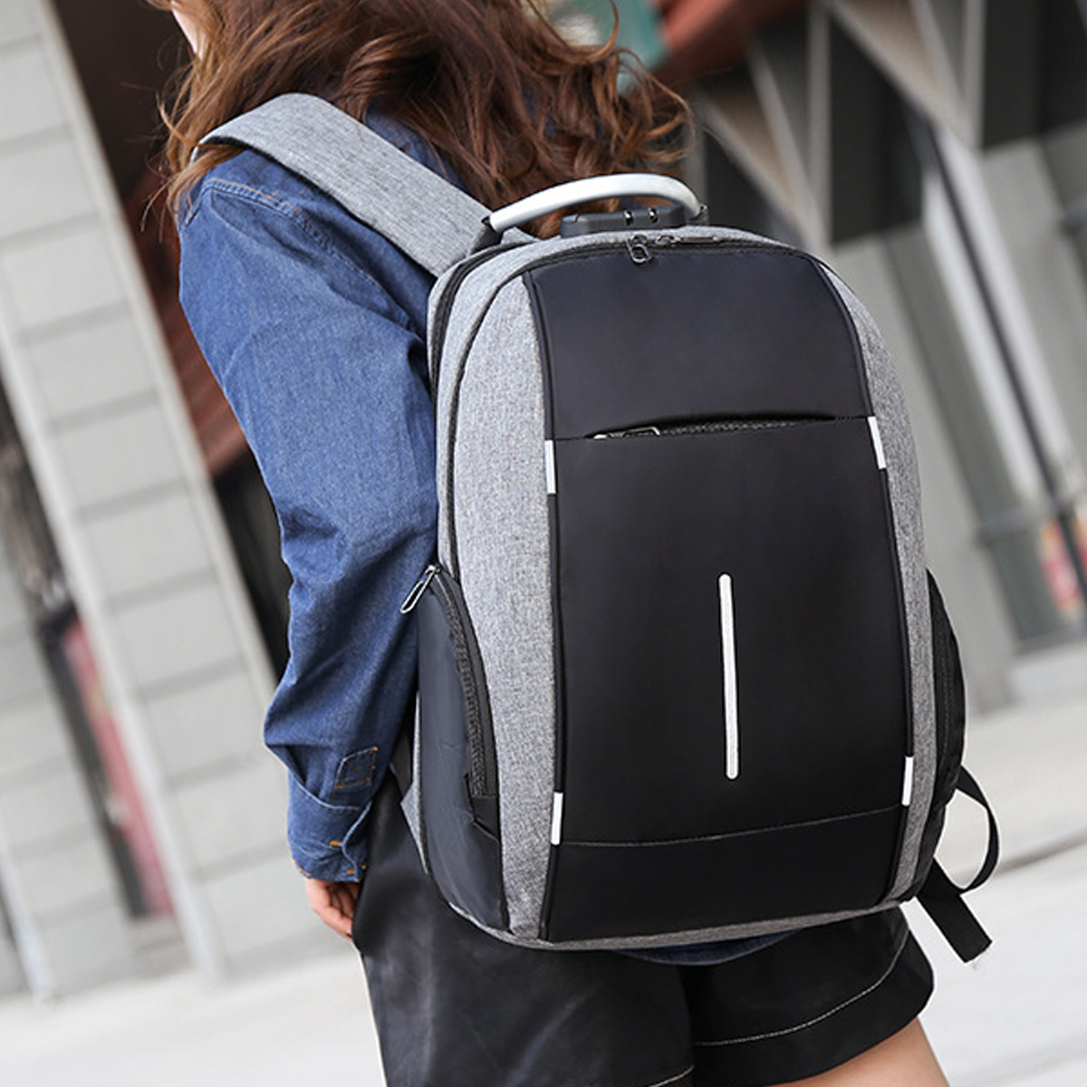 Person trägt einen grau-schwarzen Rucksack. Der Hintergrund ist ein Gebäude.