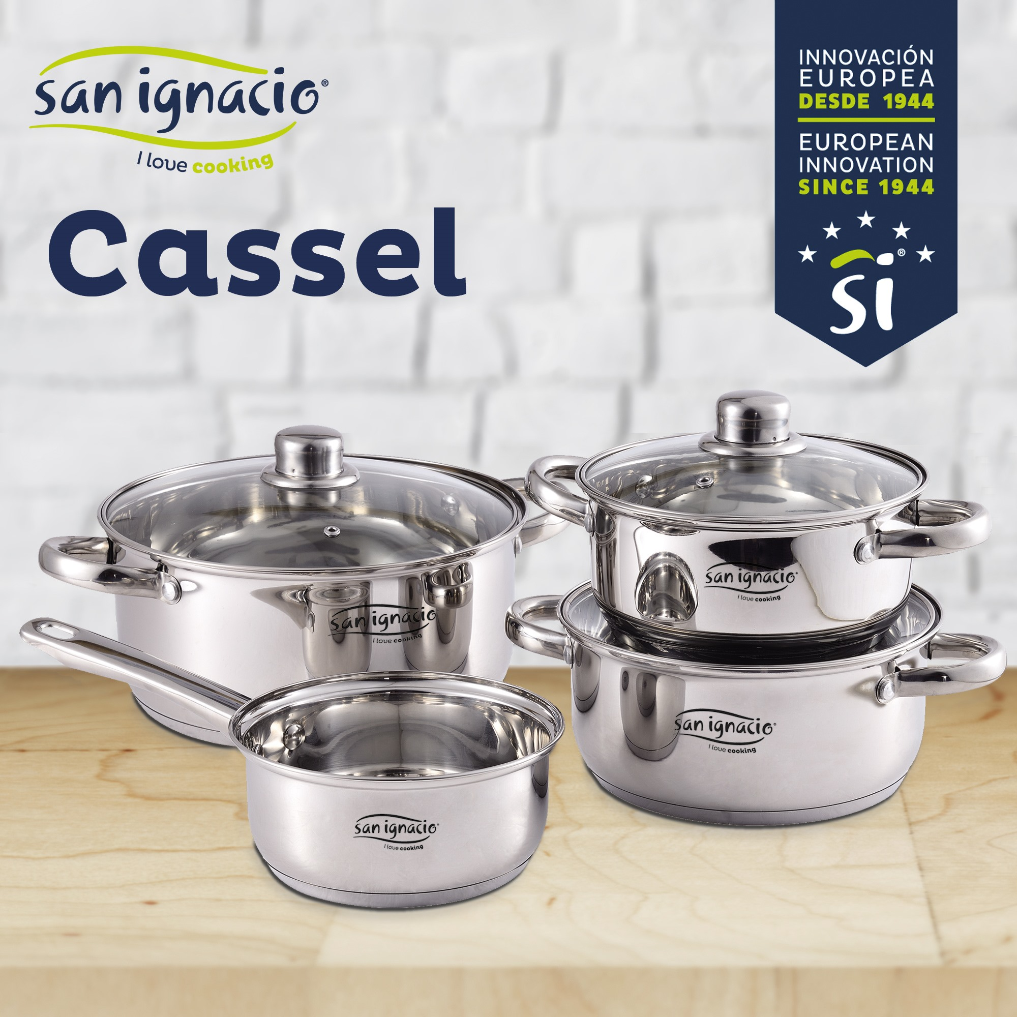 Juego de utensilios de cocina de acero inoxidable sobre superficie de madera. Incluye ollas y sartenes con tapas de vidrio. La marca es San Ignacio.