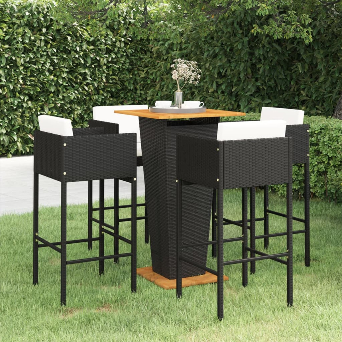 Bar-Set im Freien: schwarze Korbstühle und Tisch. Grüner Hintergrund.