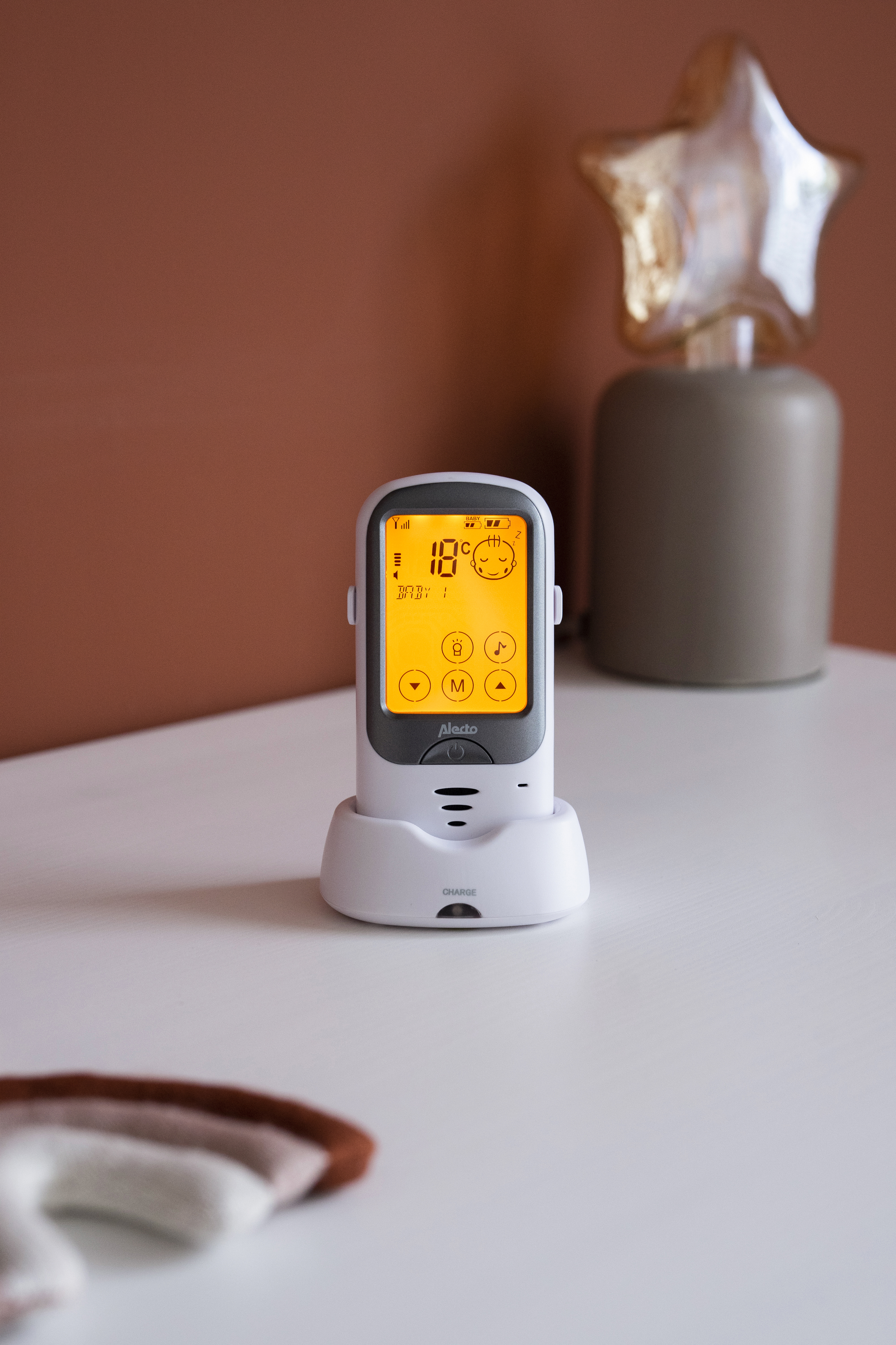 Baby monitor on a white surface, with a screen displaying information, and a star decoration.
