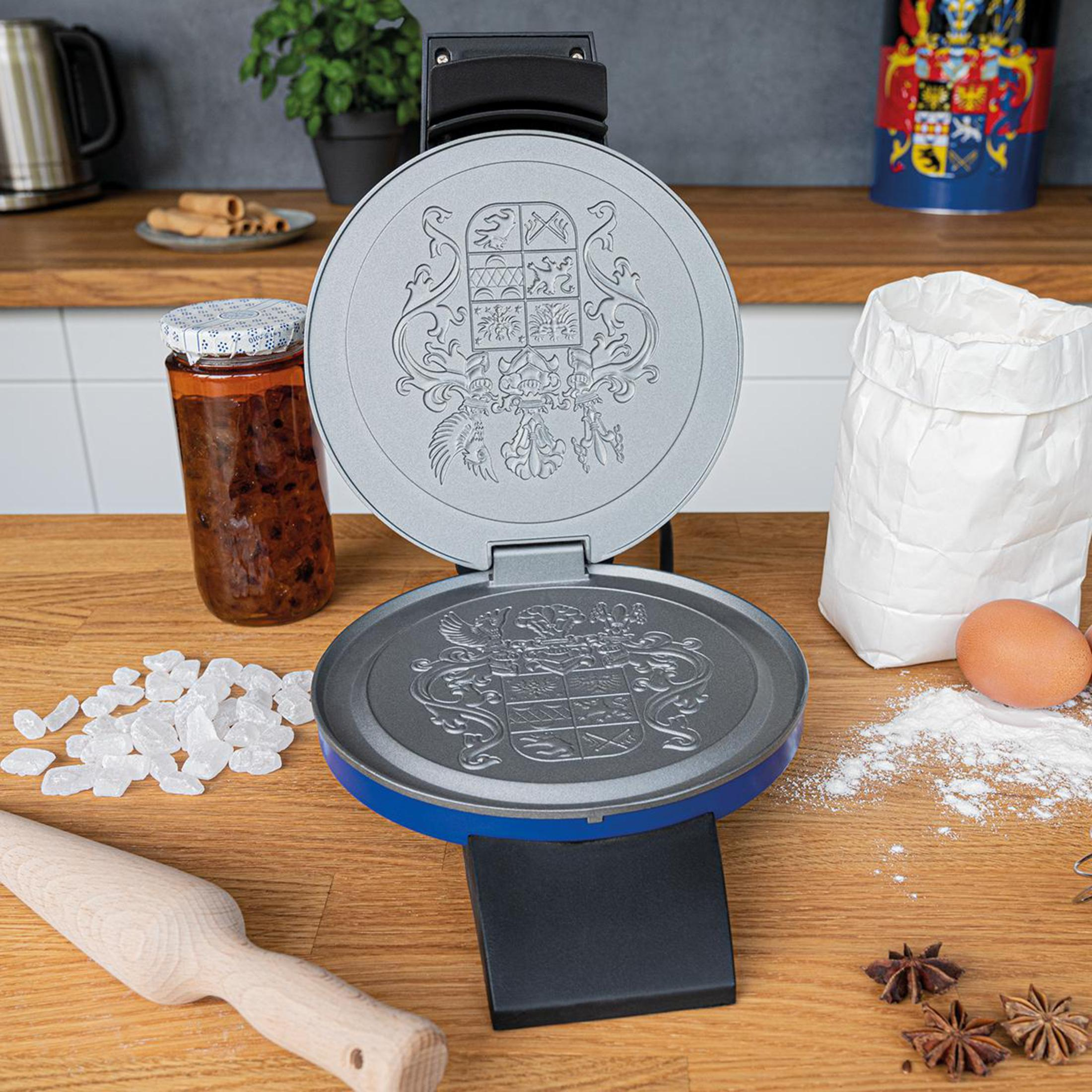 Macchina per waffle aperta su una superficie di legno, ingredienti intorno.