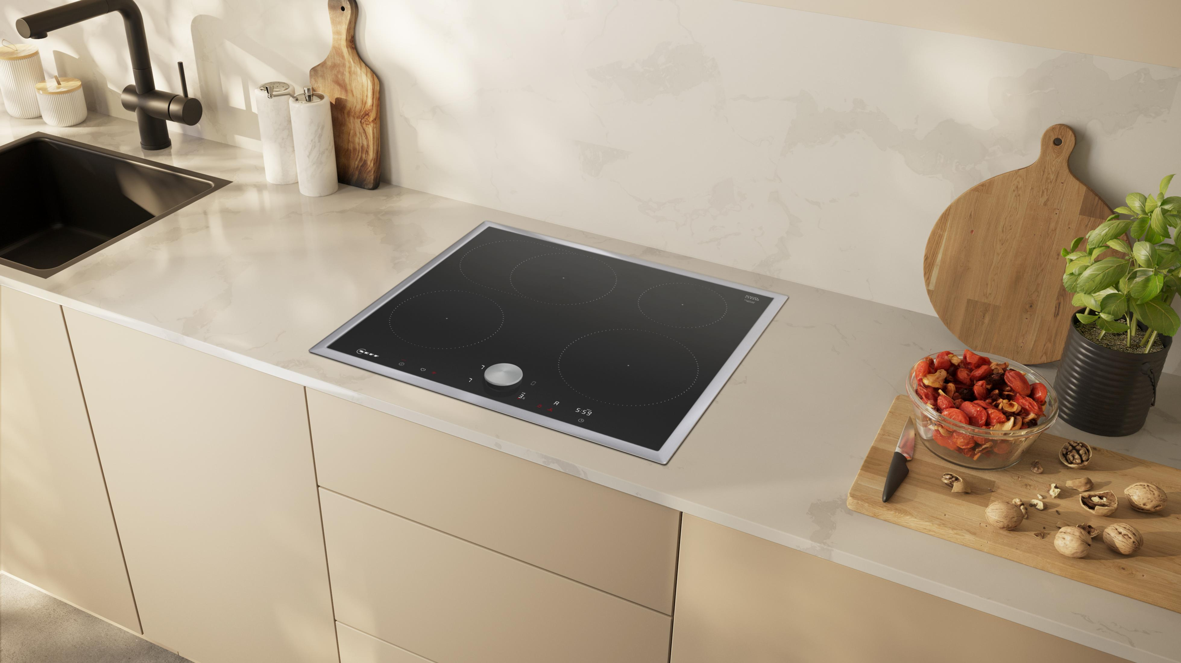 Piano cucina con piano cottura a induzione nero, alimenti e un lavello.