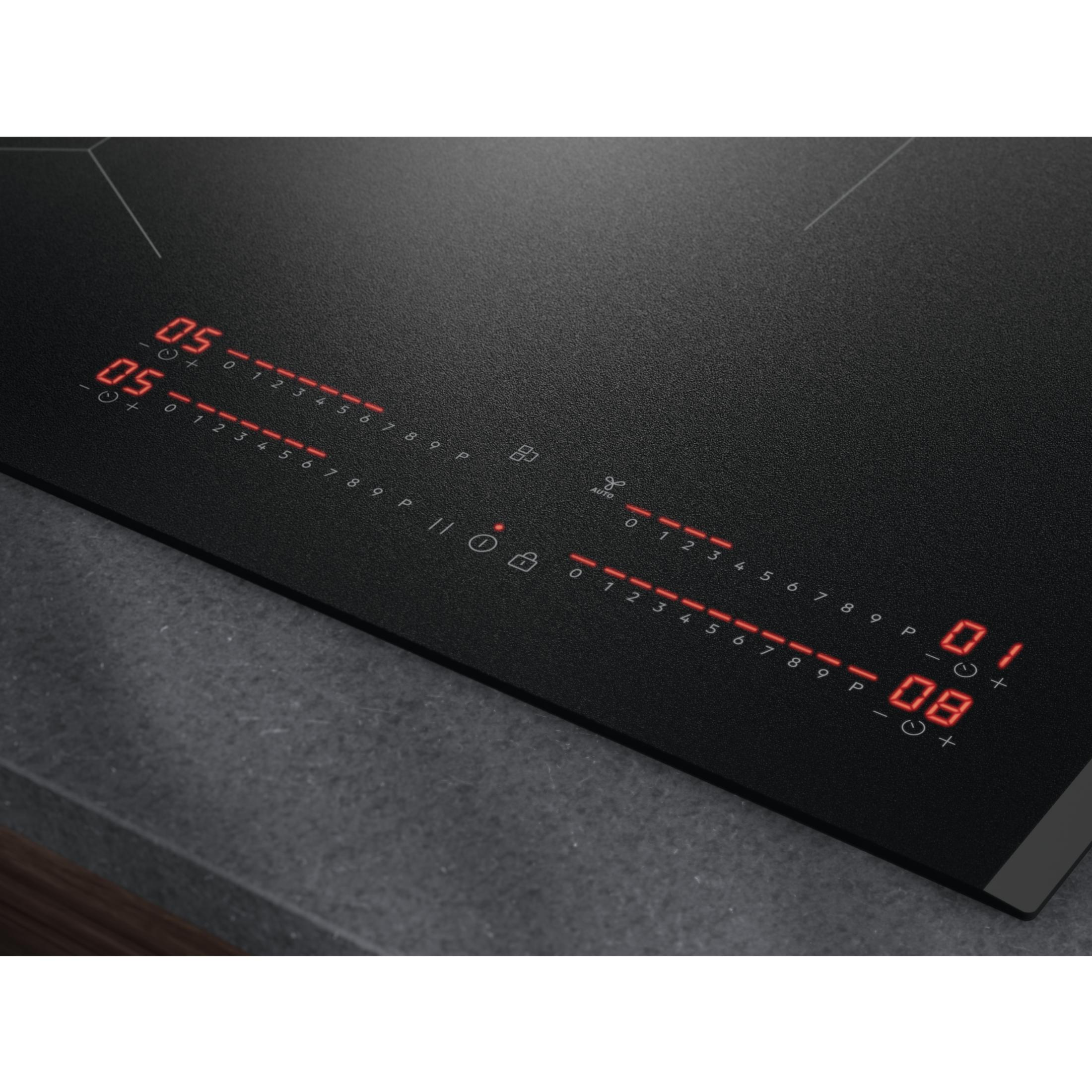 Gros plan d'une table de cuisson noire avec commandes numériques.