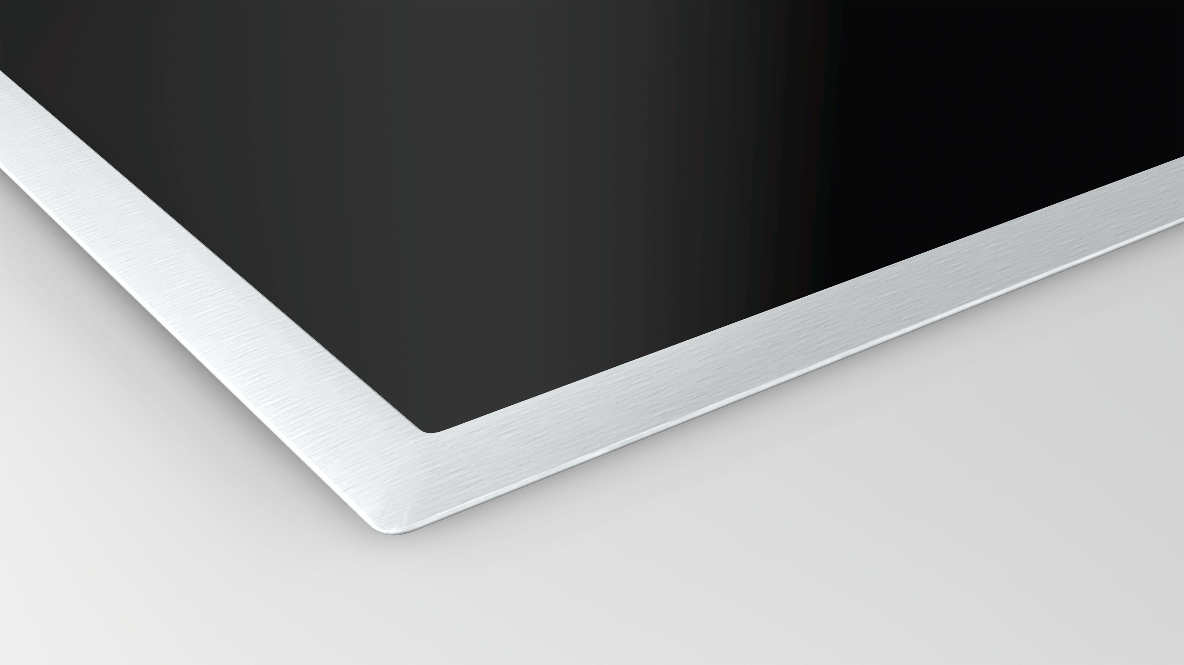 Zbliżenie czarnej płyty grzewczej ze srebrną obwódką. Nowoczesny, elegancki design.