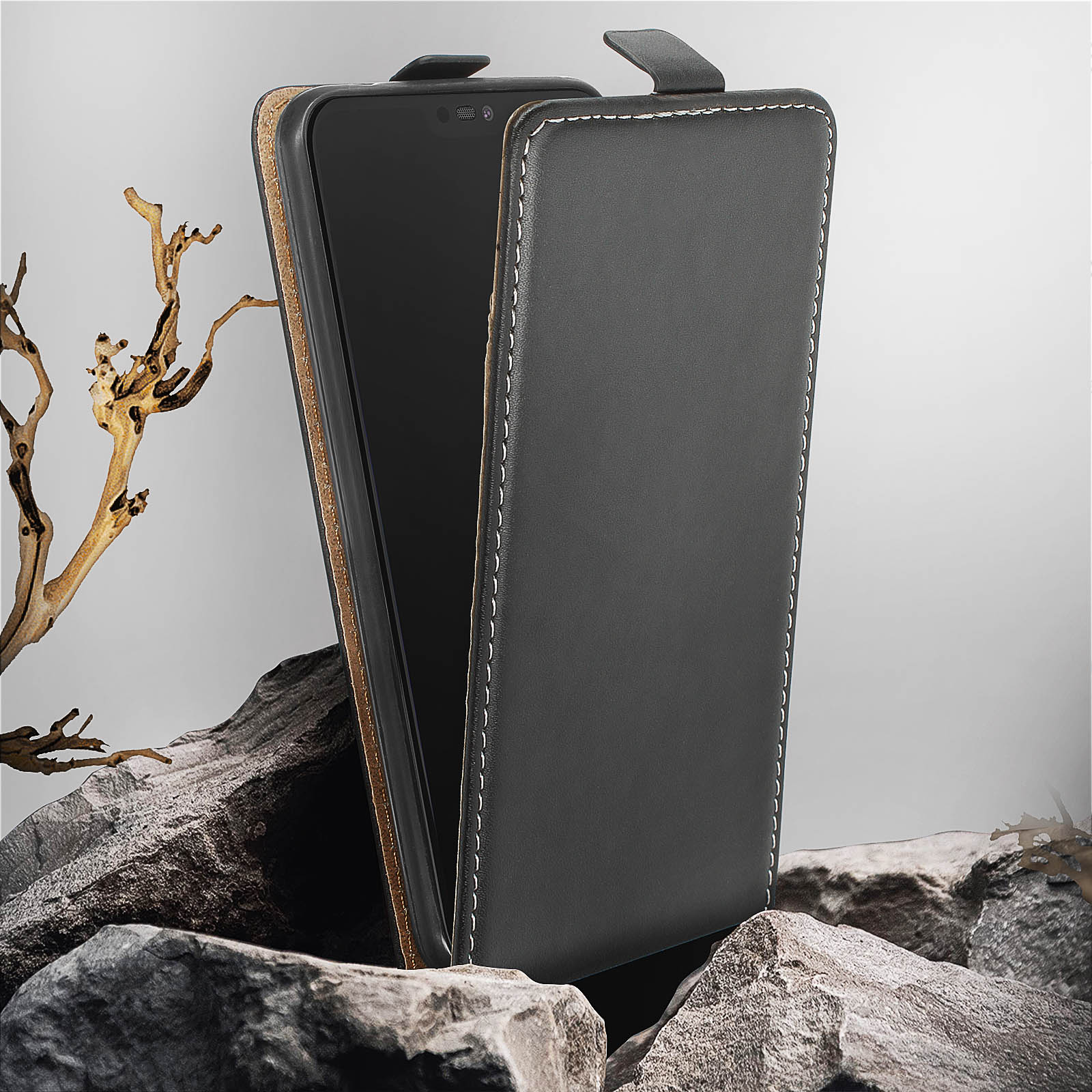 Funda de teléfono negra con teléfono dentro, de pie sobre rocas. Una rama está a la izquierda.