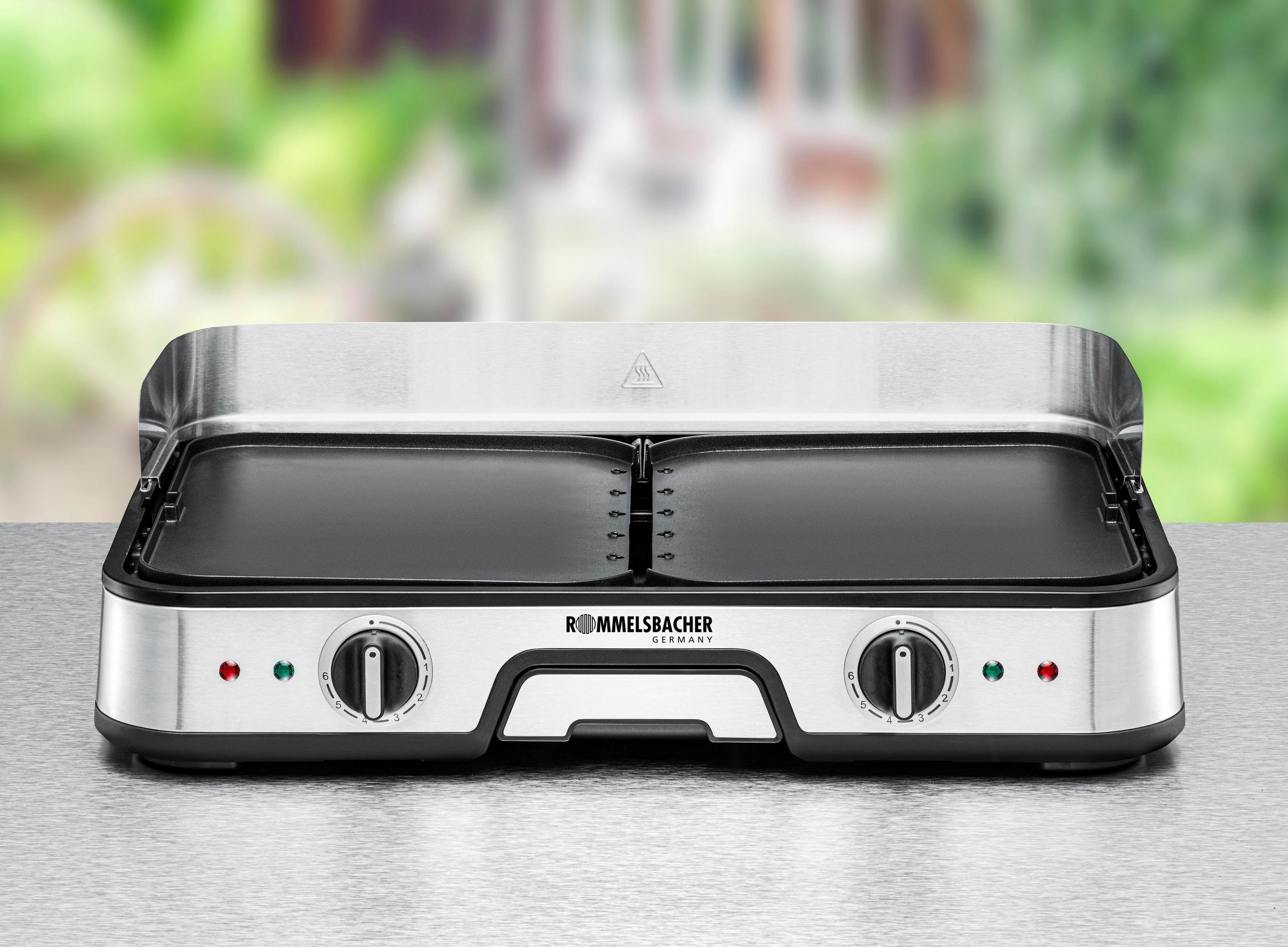 A silver and black griddle with two cooking surfaces and control knobs. It is on a silver surface.