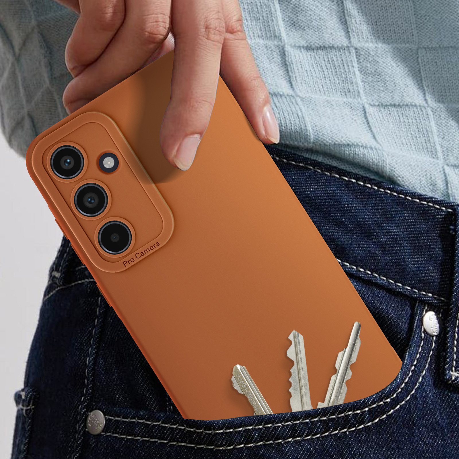 Mano in tasca dei jeans che tiene un telefono con custodia arancione e chiavi.