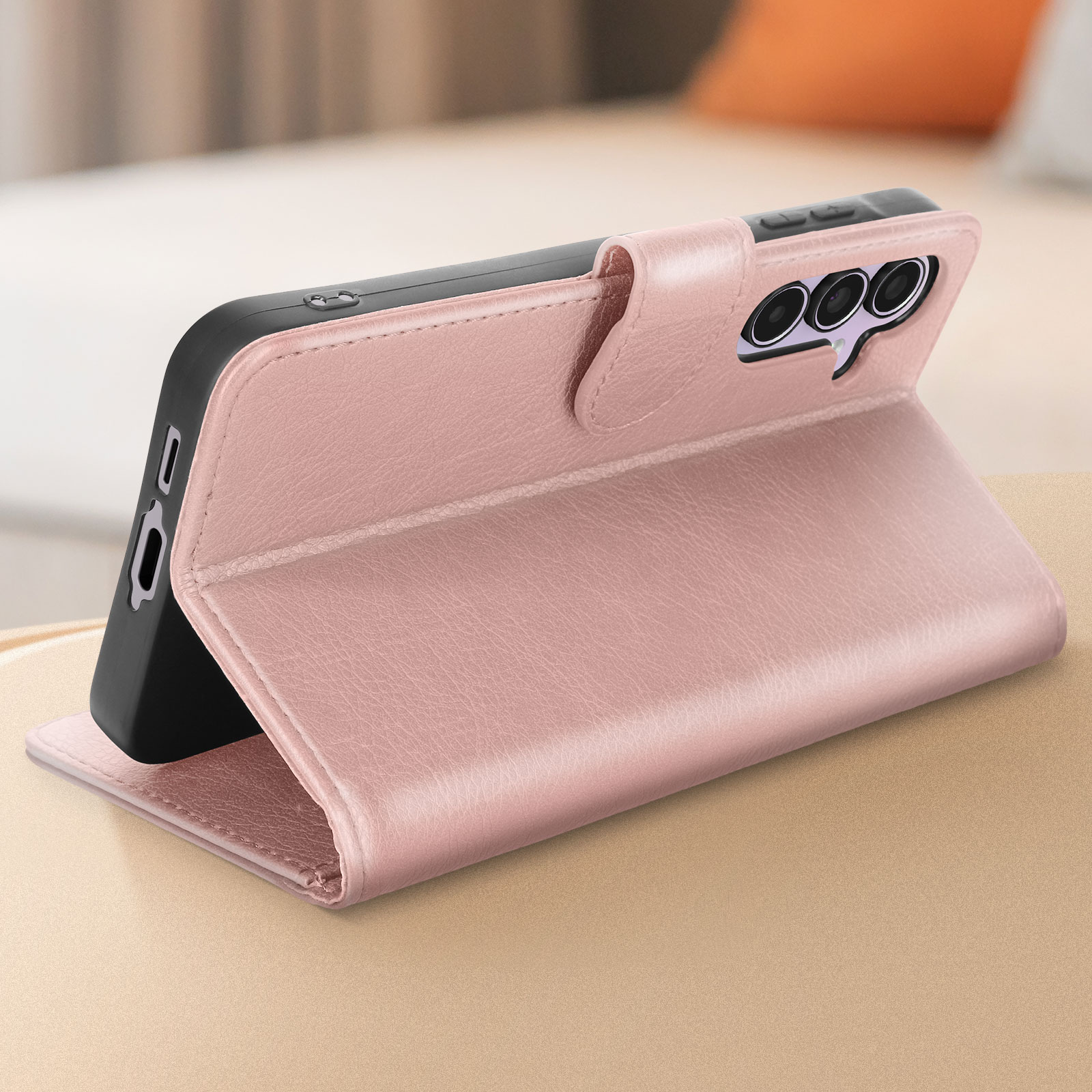 Custodia per telefono in pelle rosa, aperta e in piedi, mostra un telefono. Chiusura a bottone visibile.