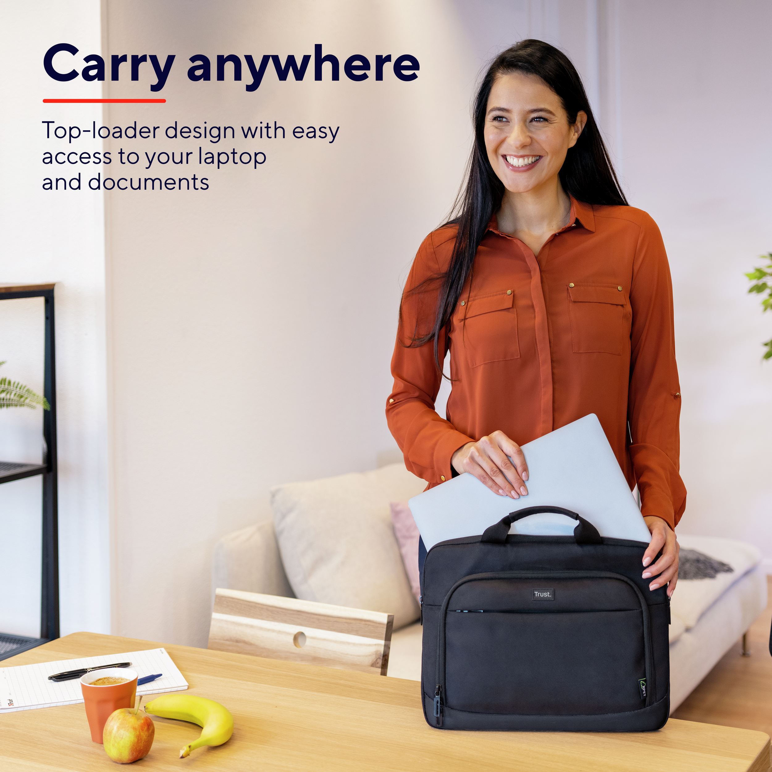 Donna con borsa per laptop, sorridente, con tavolo con frutta e quaderno.