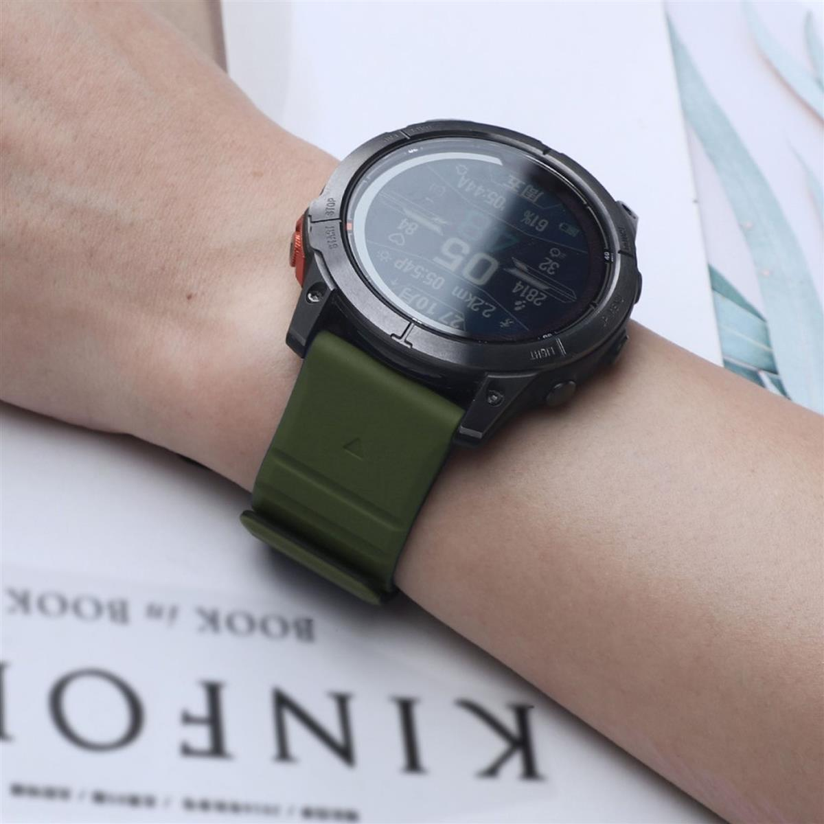 Person trägt schwarze Smartwatch mit grünem Armband. Der Bildschirm zeigt Daten.