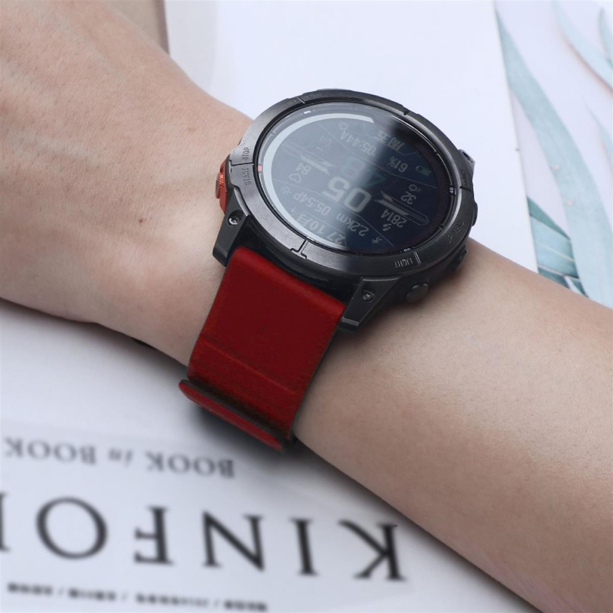 Handgelenk mit dunkelgrauer Smartwatch und rotem Armband.