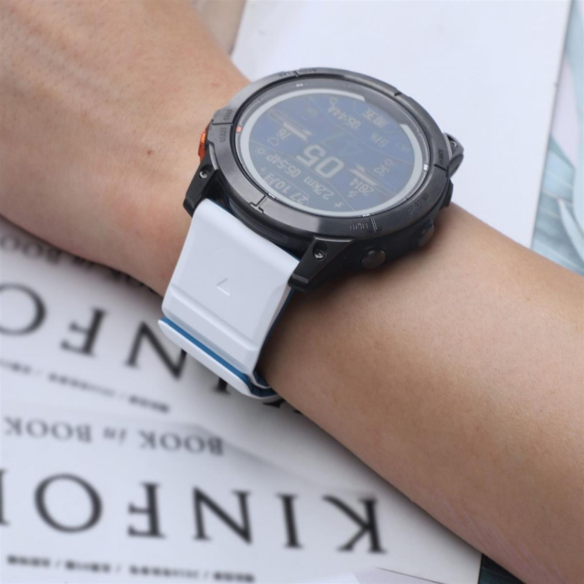 Smartwatch am Handgelenk, zeigt Zeit und andere Daten. Weißes Armband mit blauem Akzent.