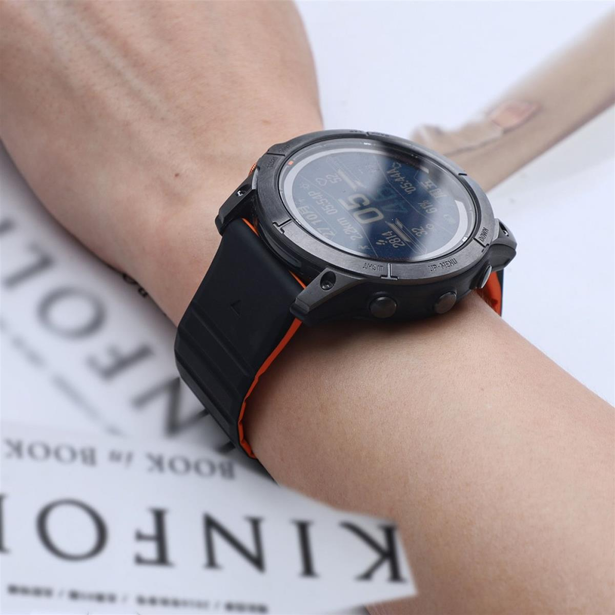 Eine Smartwatch am Handgelenk mit digitaler Anzeige, die Zeit und Metriken zeigt, mit einem Buch.