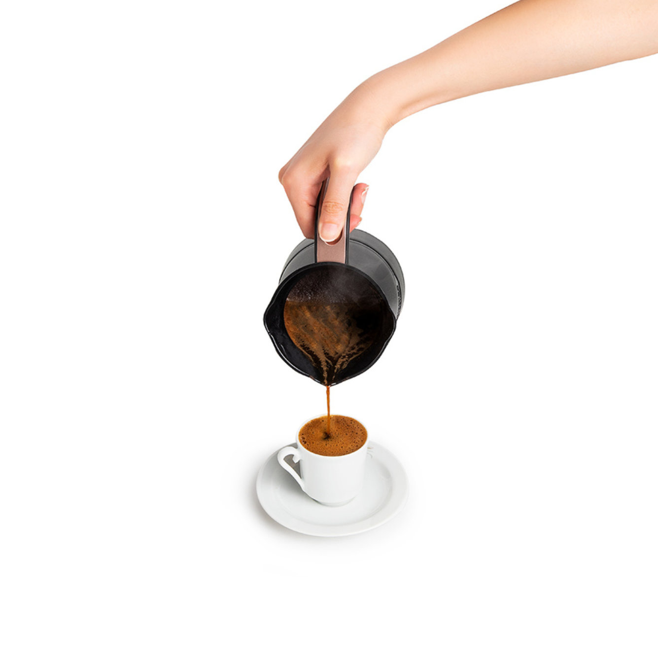 Eine Hand gießt Kaffee aus einer schwarzen Kanne in eine weiße Tasse, auf weißem Hintergrund.