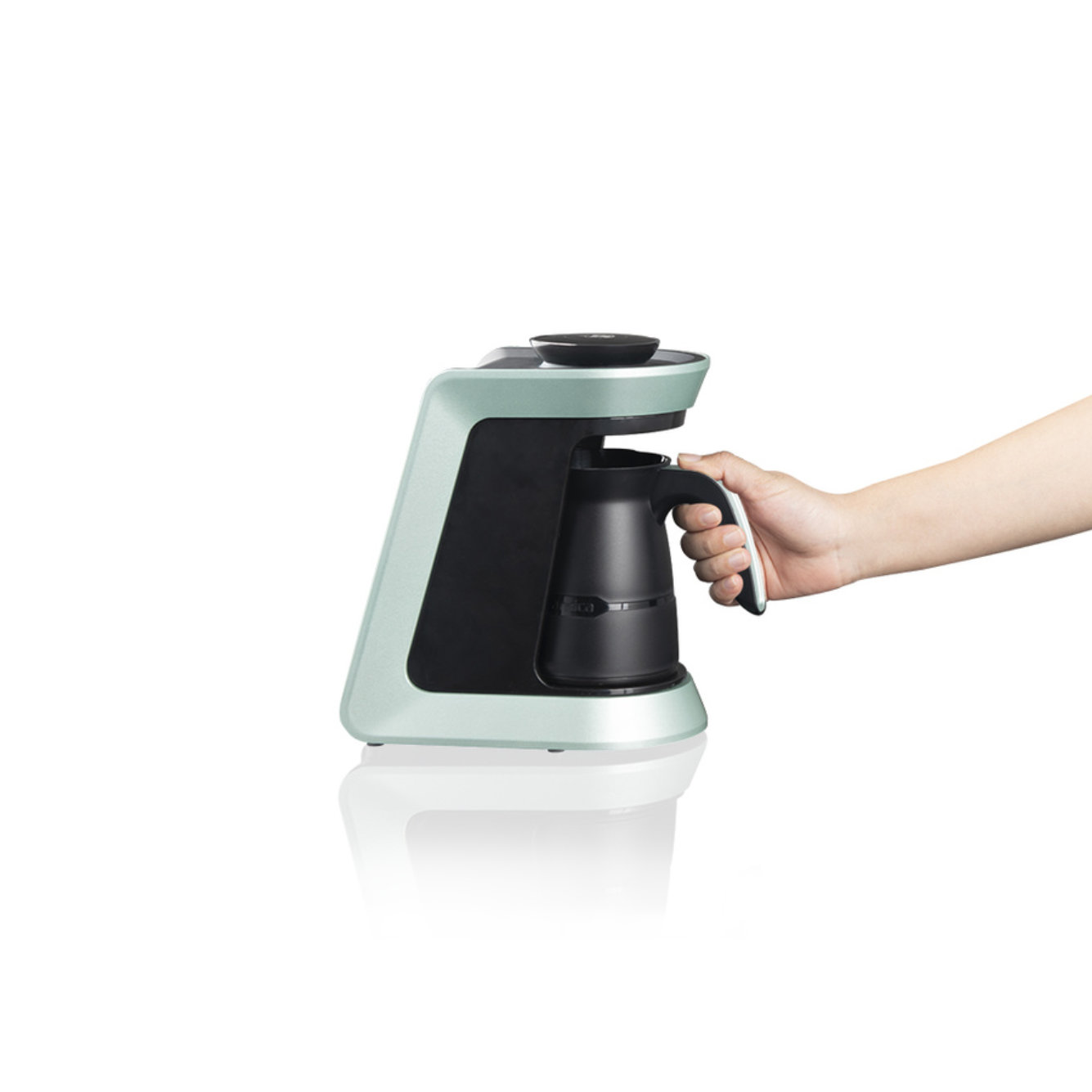Eine mintgrüne Kaffeemaschine mit einer schwarzen Karaffe. Eine Hand hält die Karaffe.