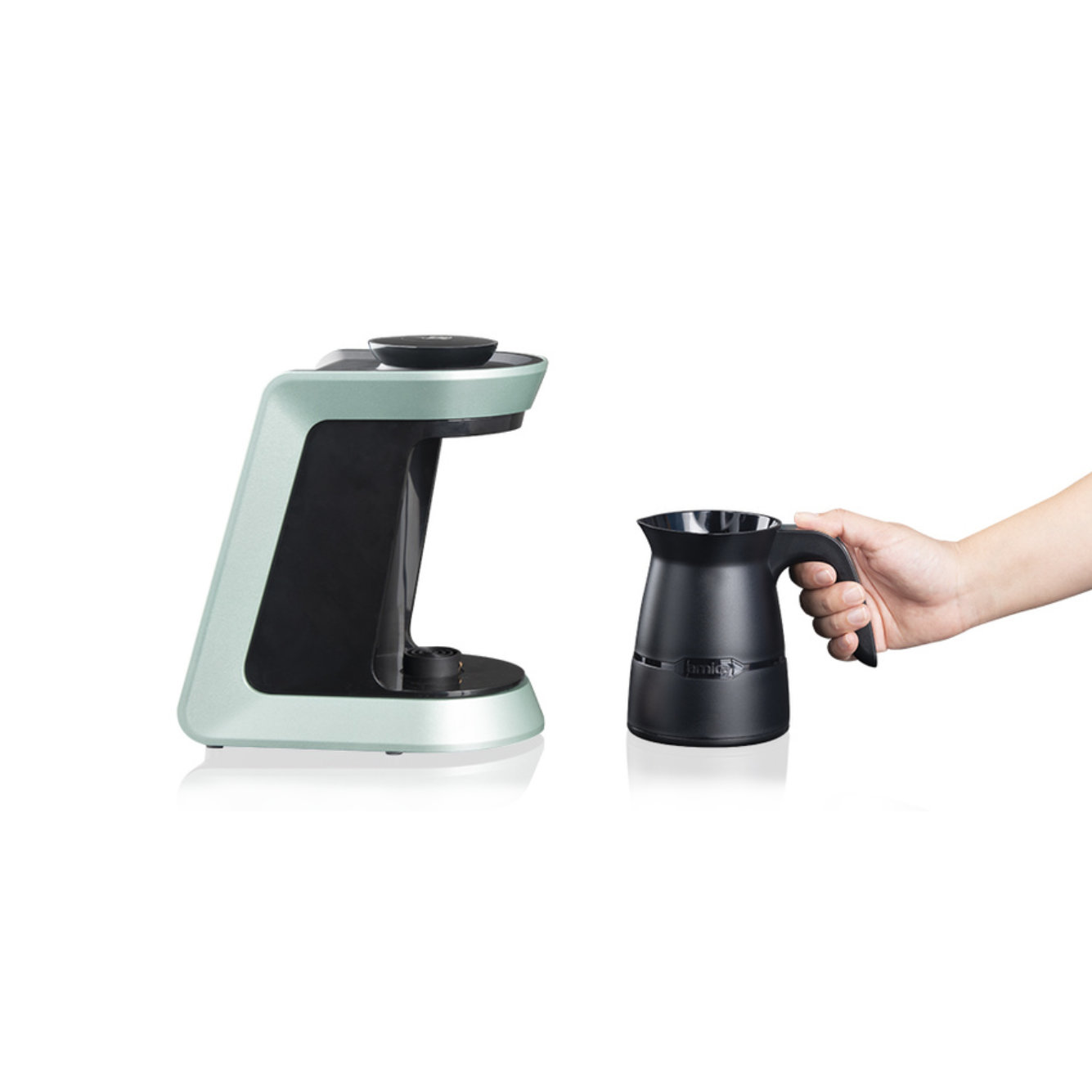 Ein mintgrüner Kaffeezubereiter und eine schwarze Kaffeekanne. Eine Hand hält die Kanne.