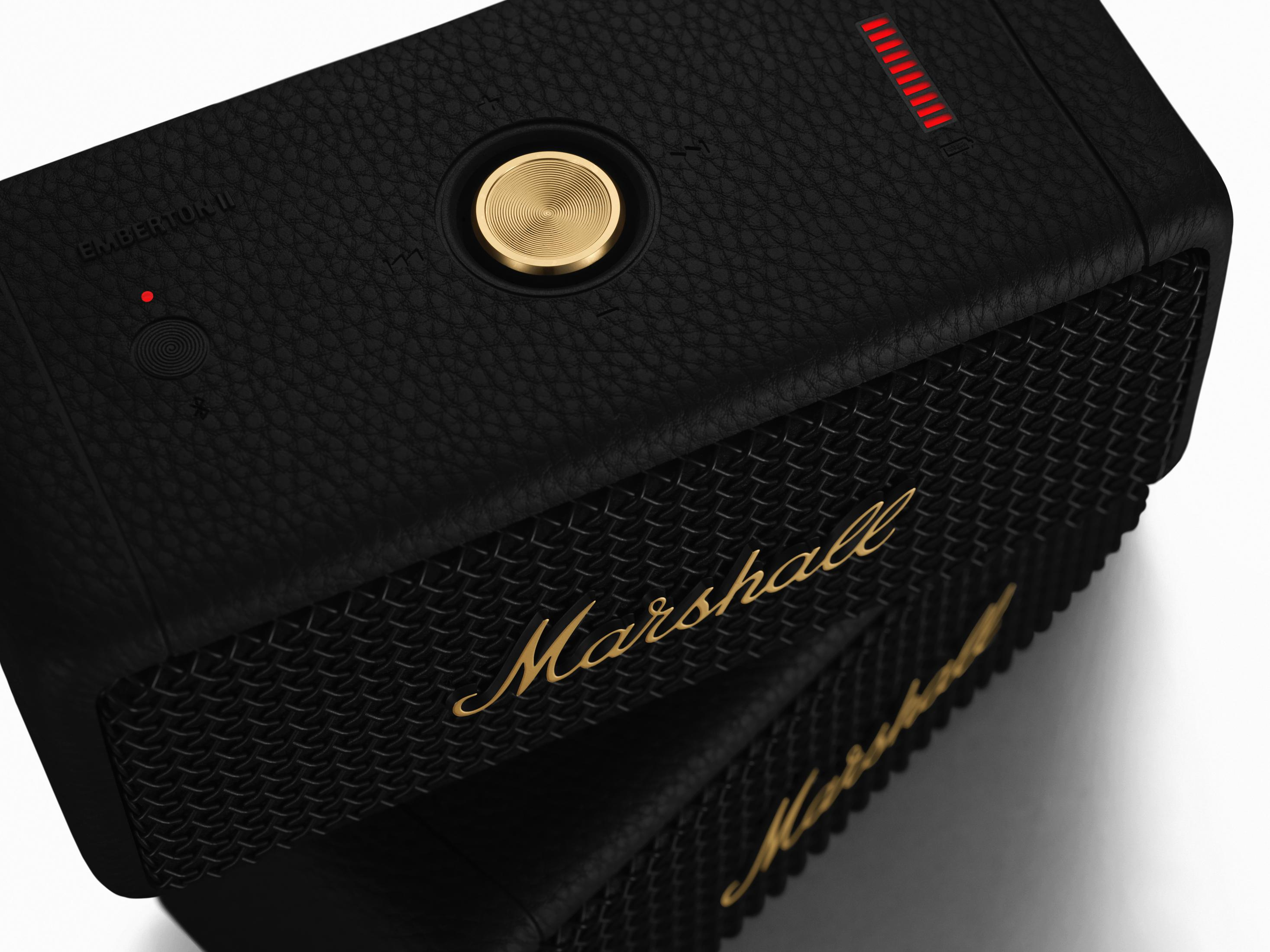 Primer plano de un altavoz Marshall negro con logotipo dorado y mando. Rejilla negra.